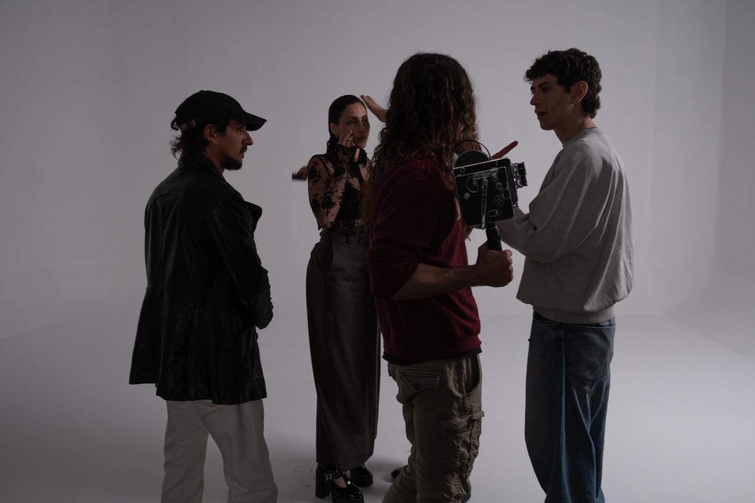 Sei persone sedute su un divano durante le riprese di una produzione video professionale in un soggiorno, riprese da dietro la telecamera.