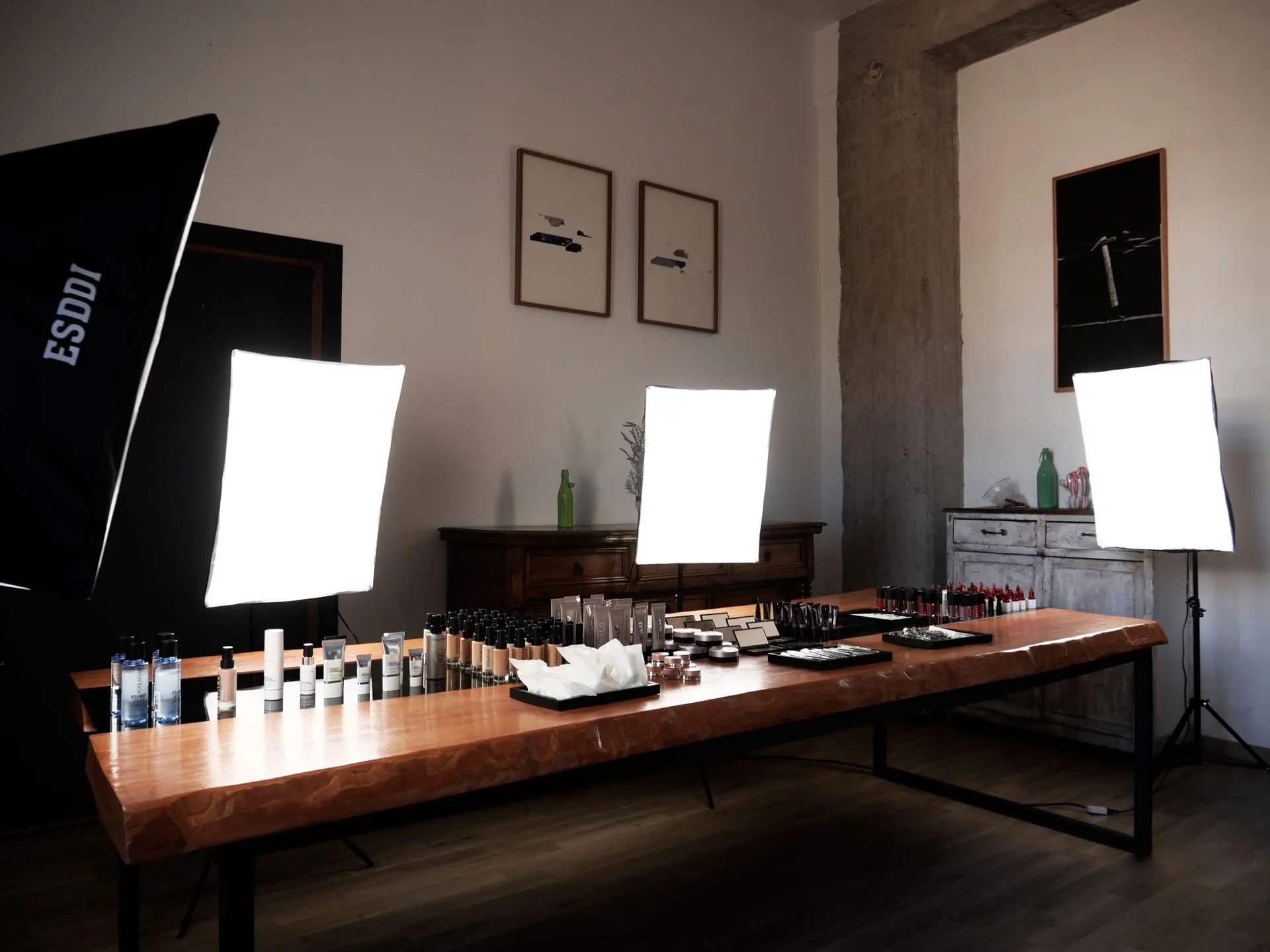 Un tavolo di legno allestito per un servizio fotografico di prodotti, con diverse luci softbox, attrezzature professionali e prodotti di bellezza.