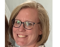 Amy Drake smiles in front of a white wall