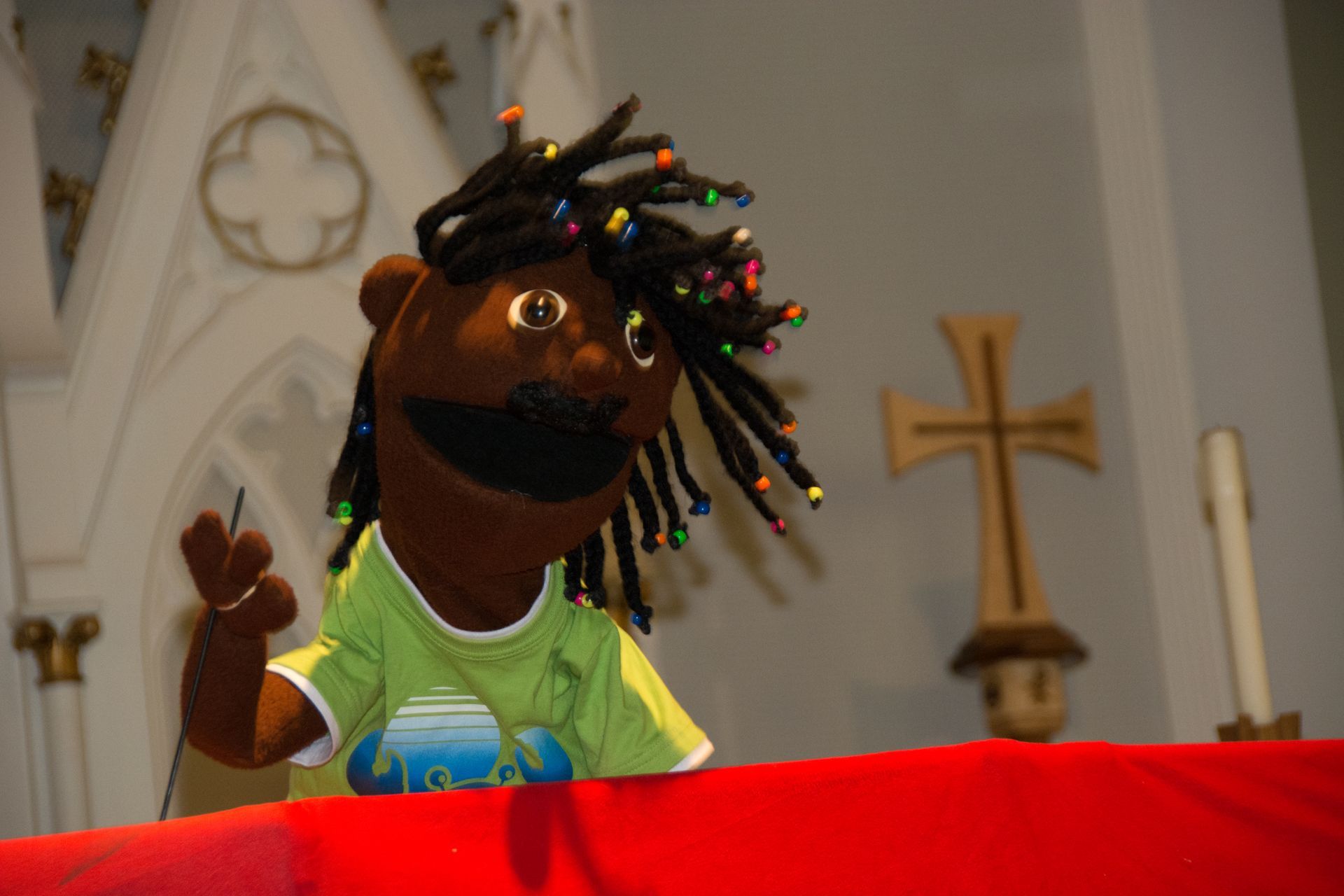 A puppet smiles and waves in a church sanctuary