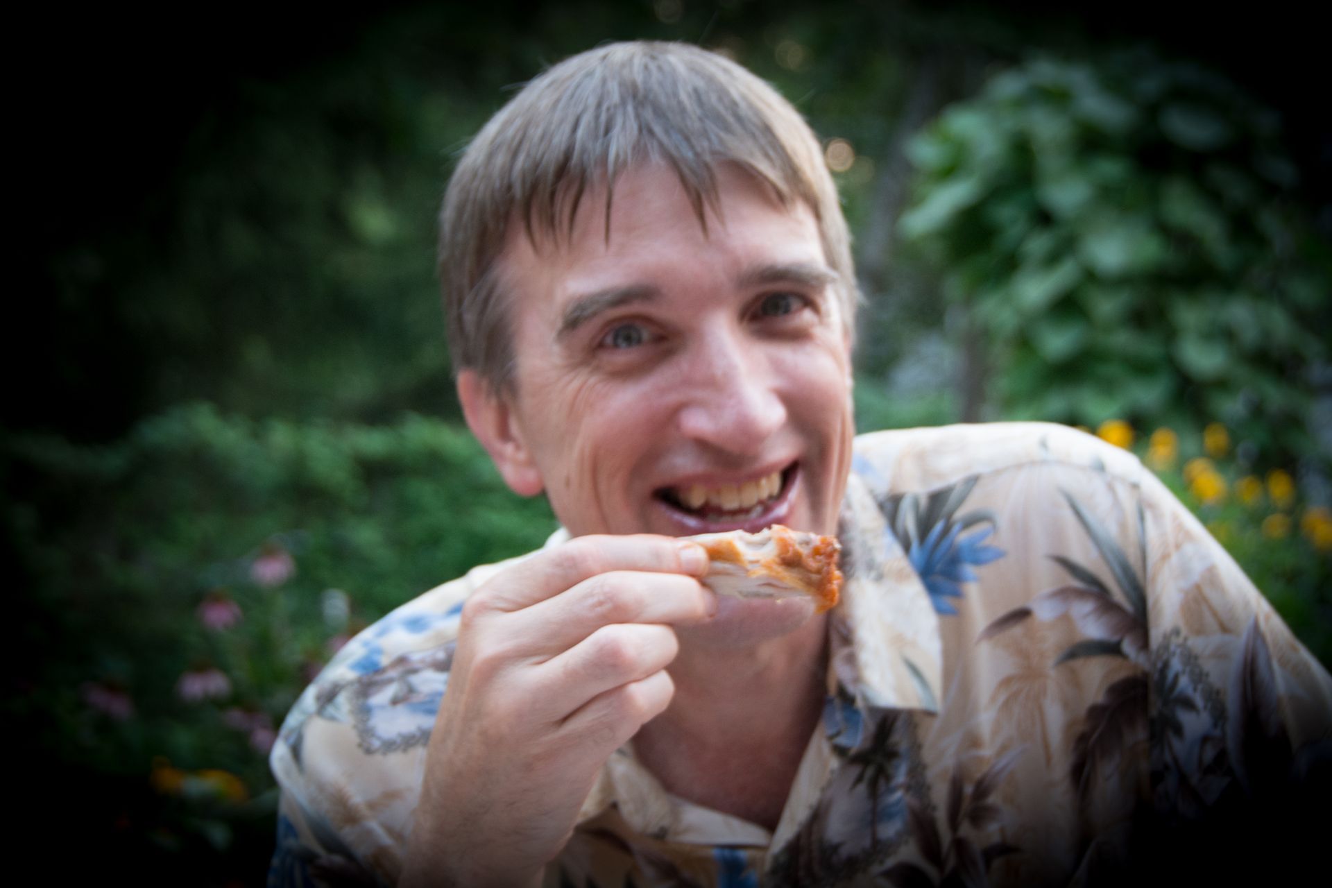 A man smiles while eating a taco