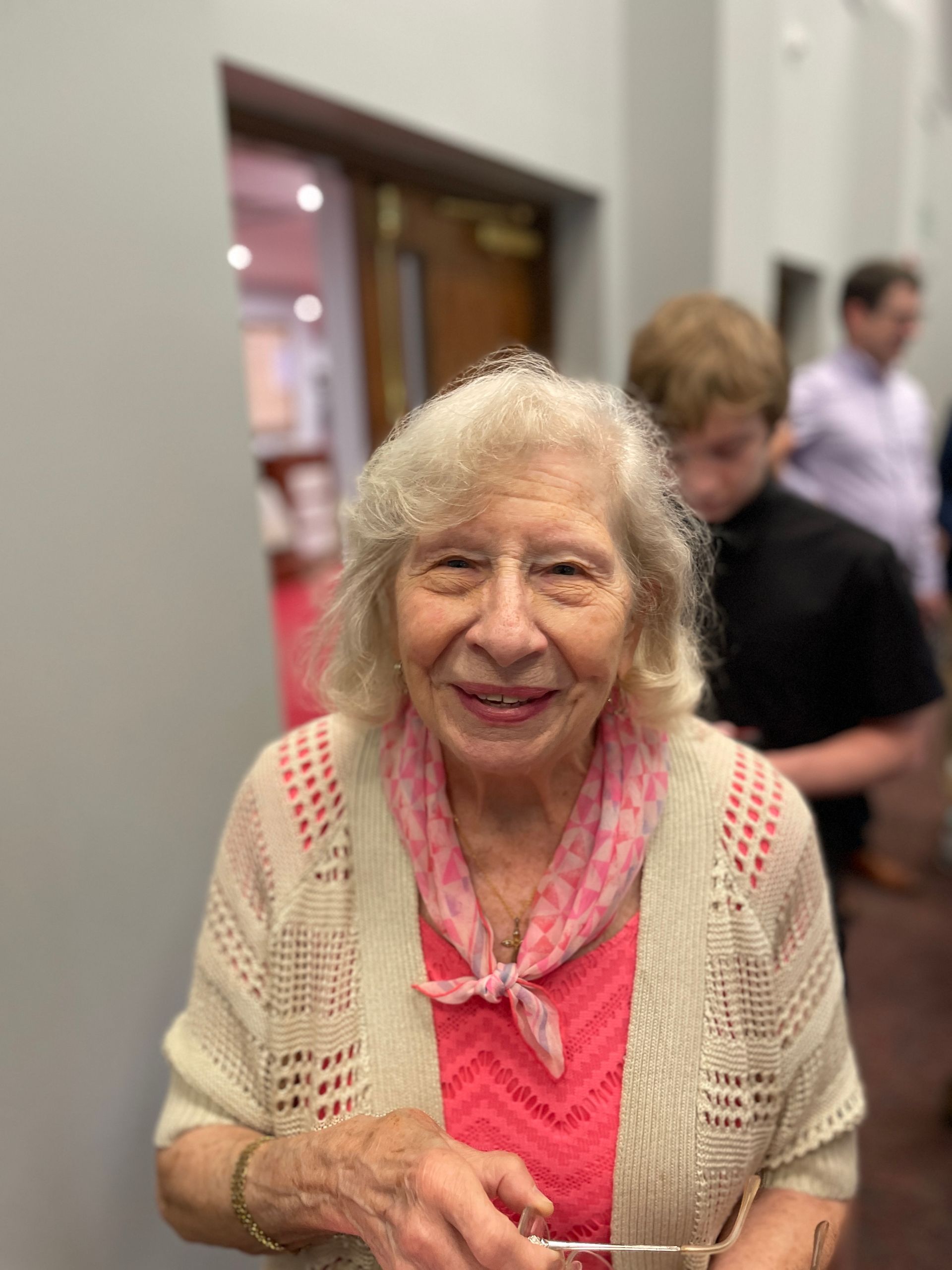 A woman smiles in front of a crowded room