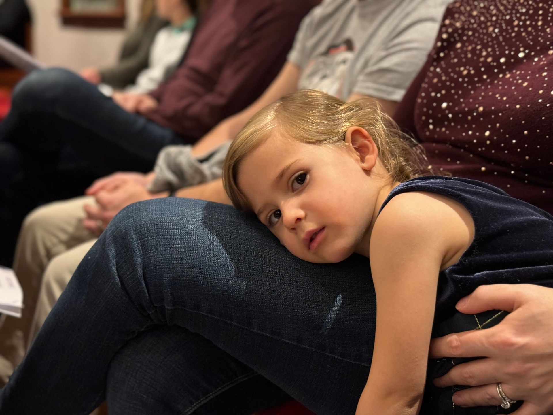 A child leans on her parents knee