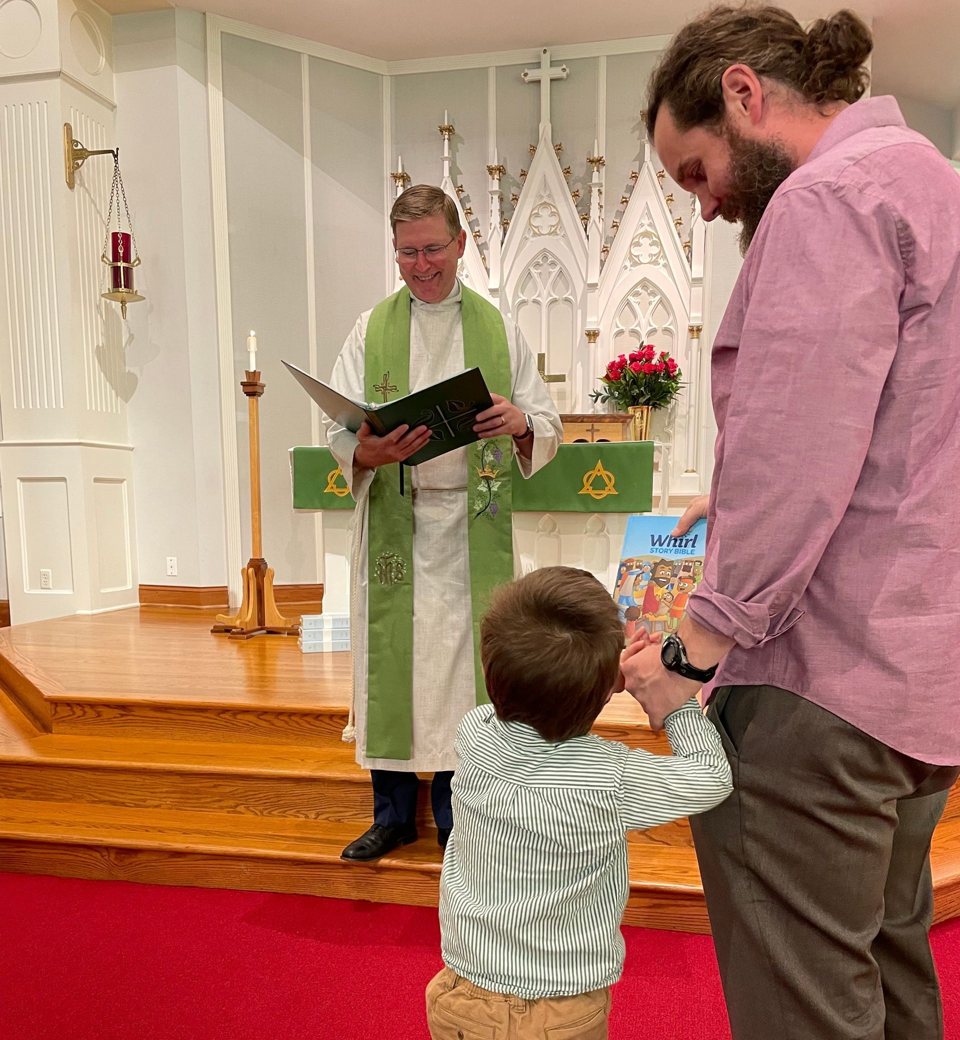 A Pastor reads prayers from a book, a man bows in head in prayer to his right