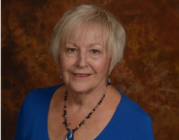 Judy McLeod smiles in front of a brown background