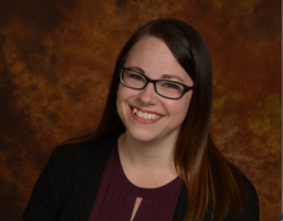 Karla Kruse smiles in front of a brown background