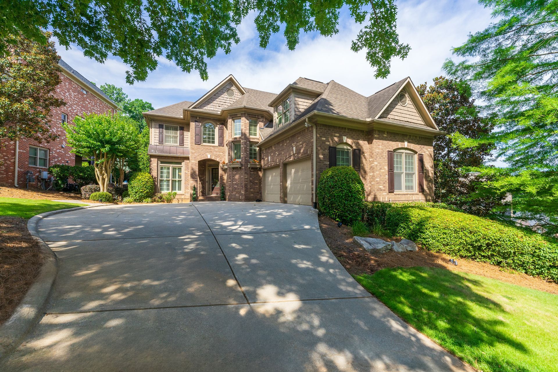 A large brick house with a concrete driveway leading up to it.