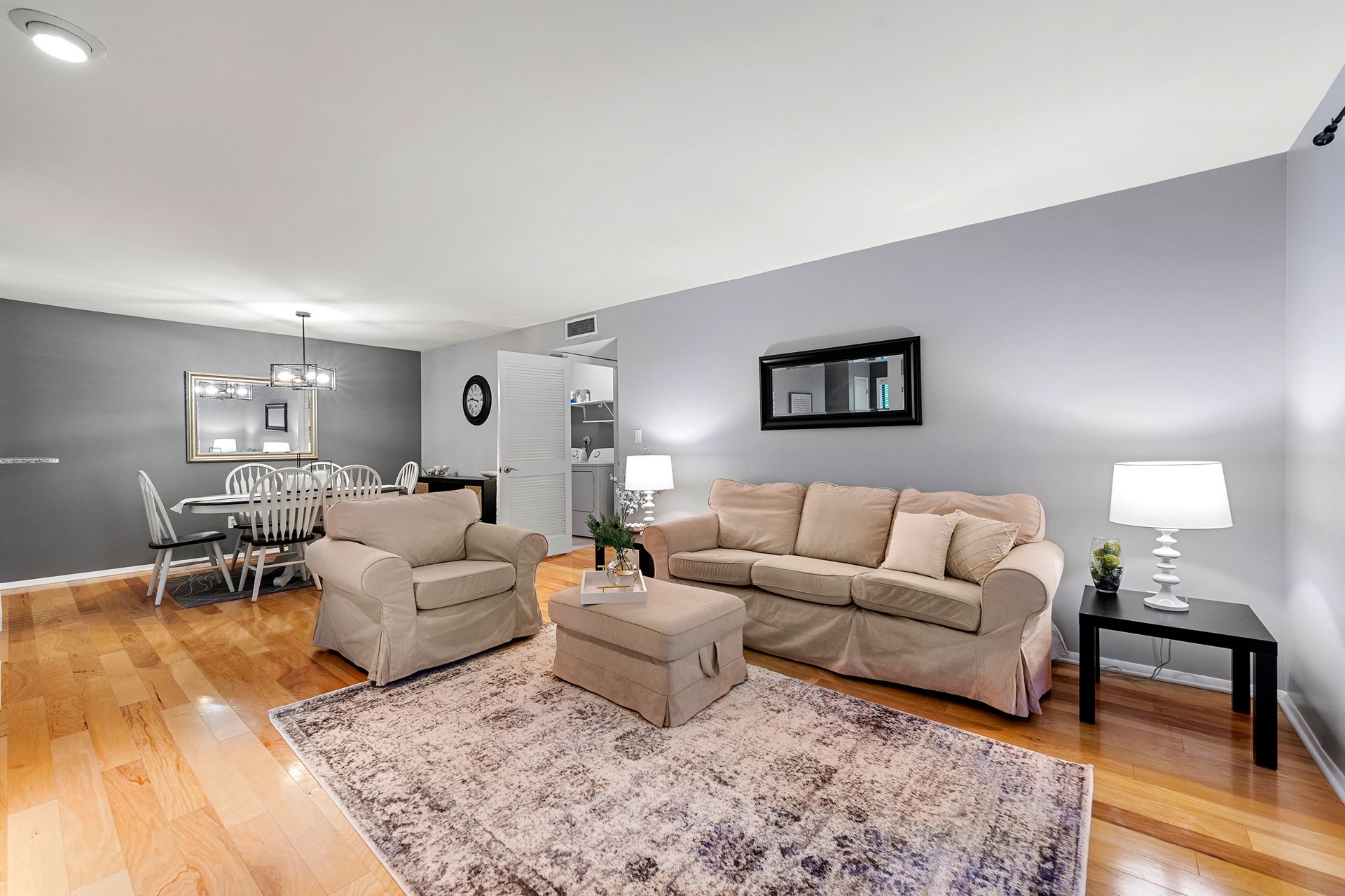 A living room with a couch , chair , ottoman and rug.