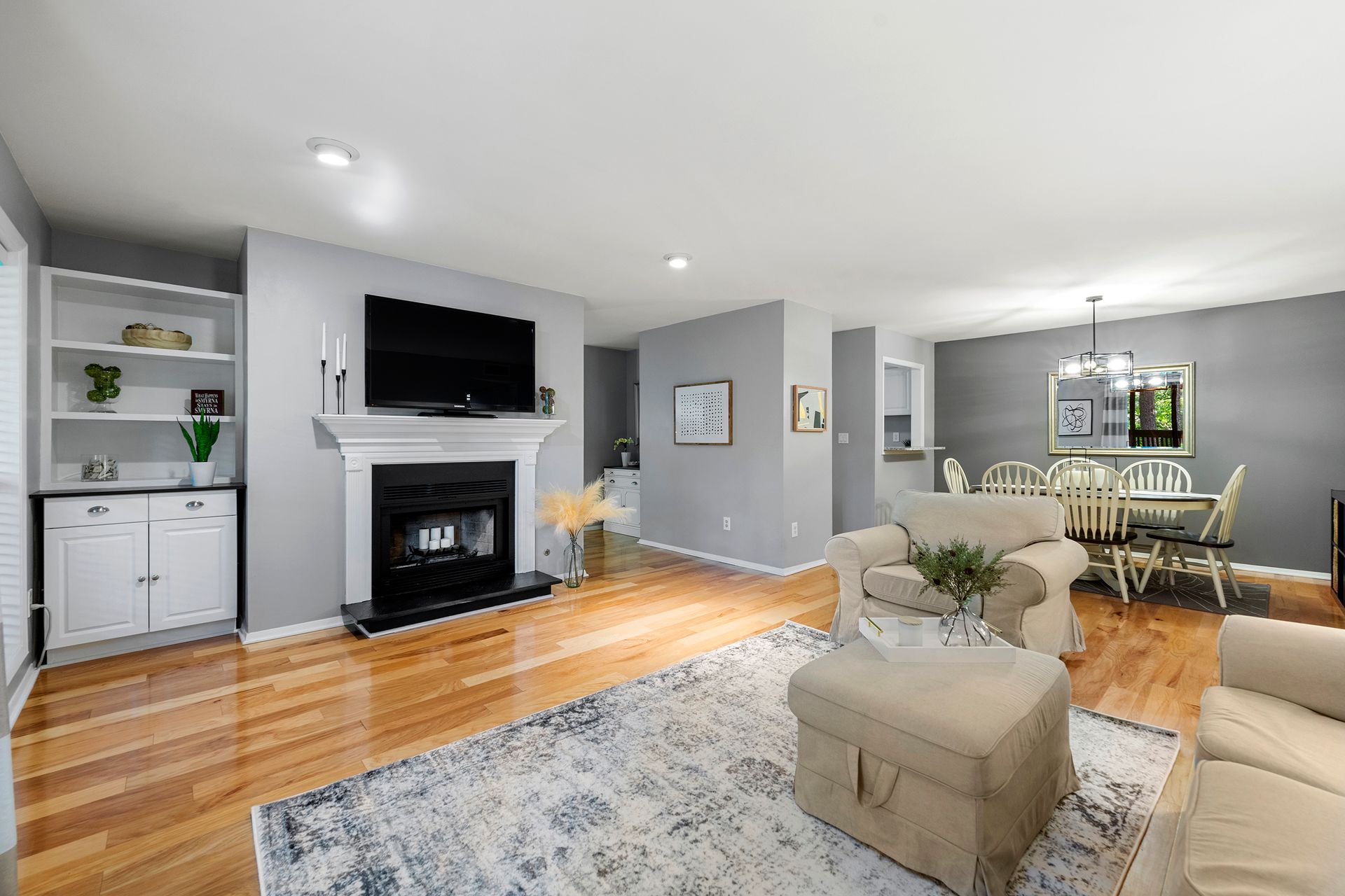 A living room with a fireplace , couch , chairs , ottoman and television.