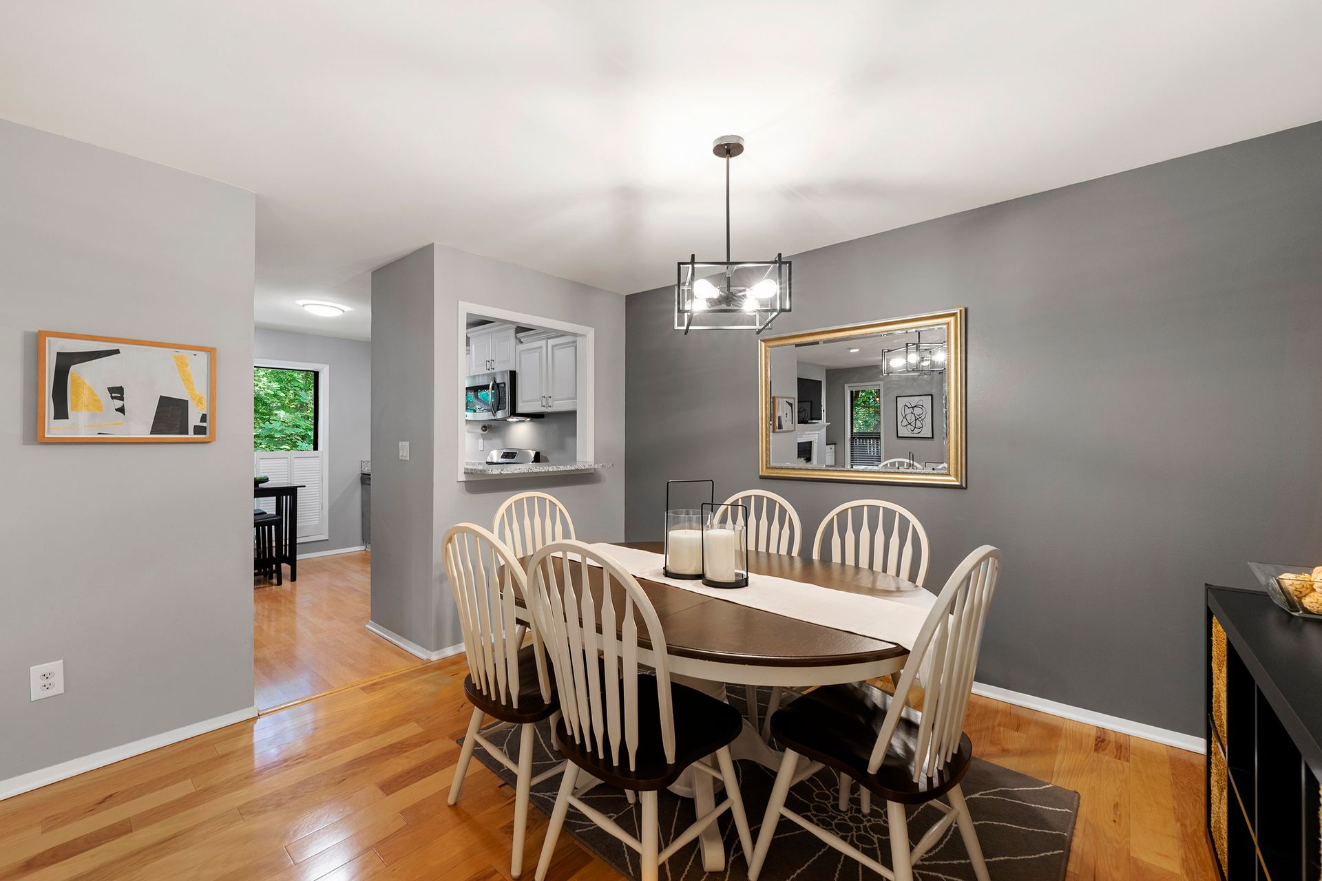 A dining room with a table and chairs and a mirror.