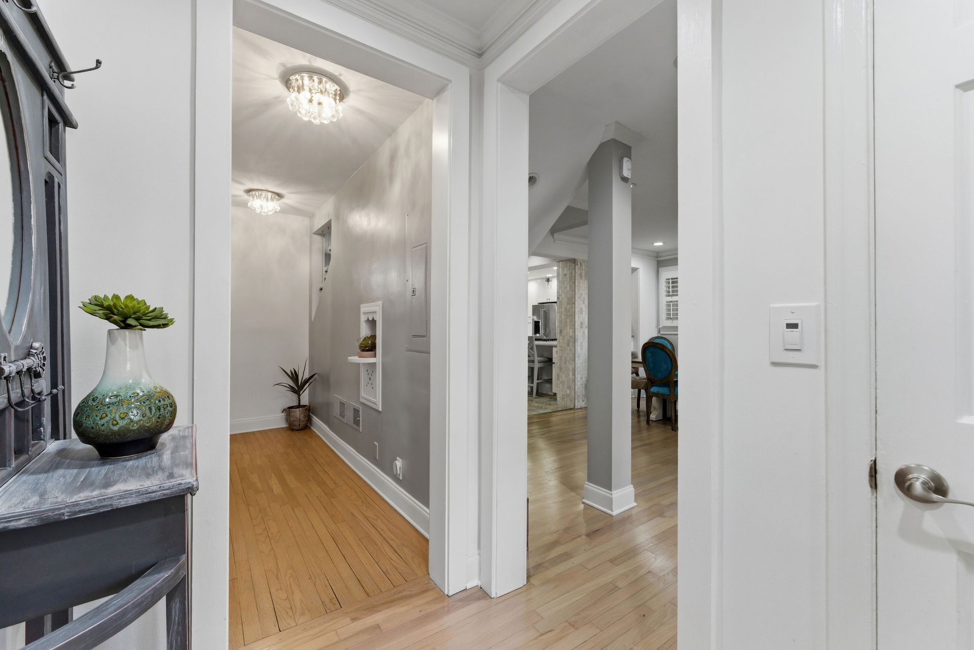 A view through two arched doorways into a bright hallway and living area with light wood floors and white trim.