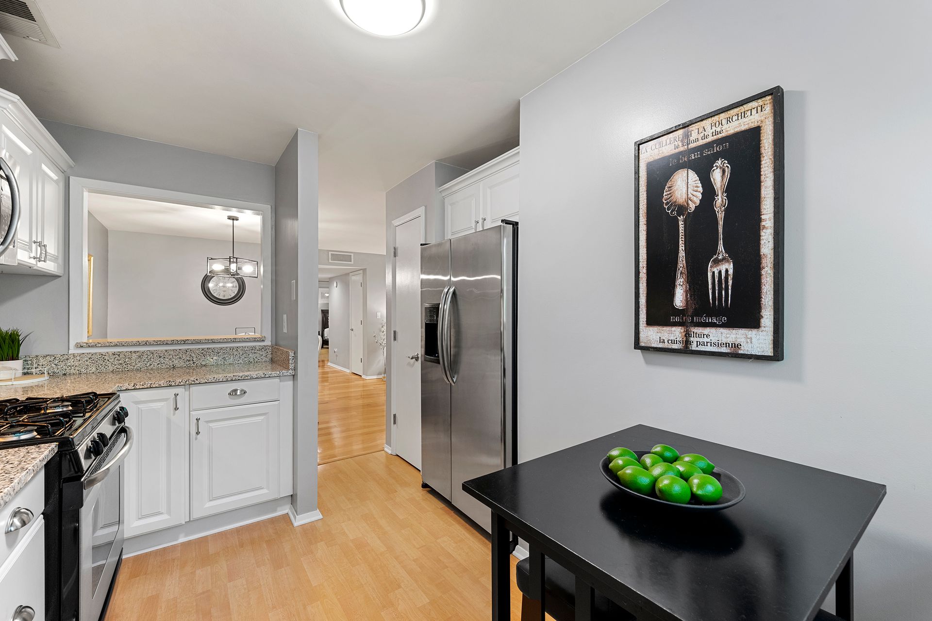 A kitchen with a black table and a bowl of green apples on it.