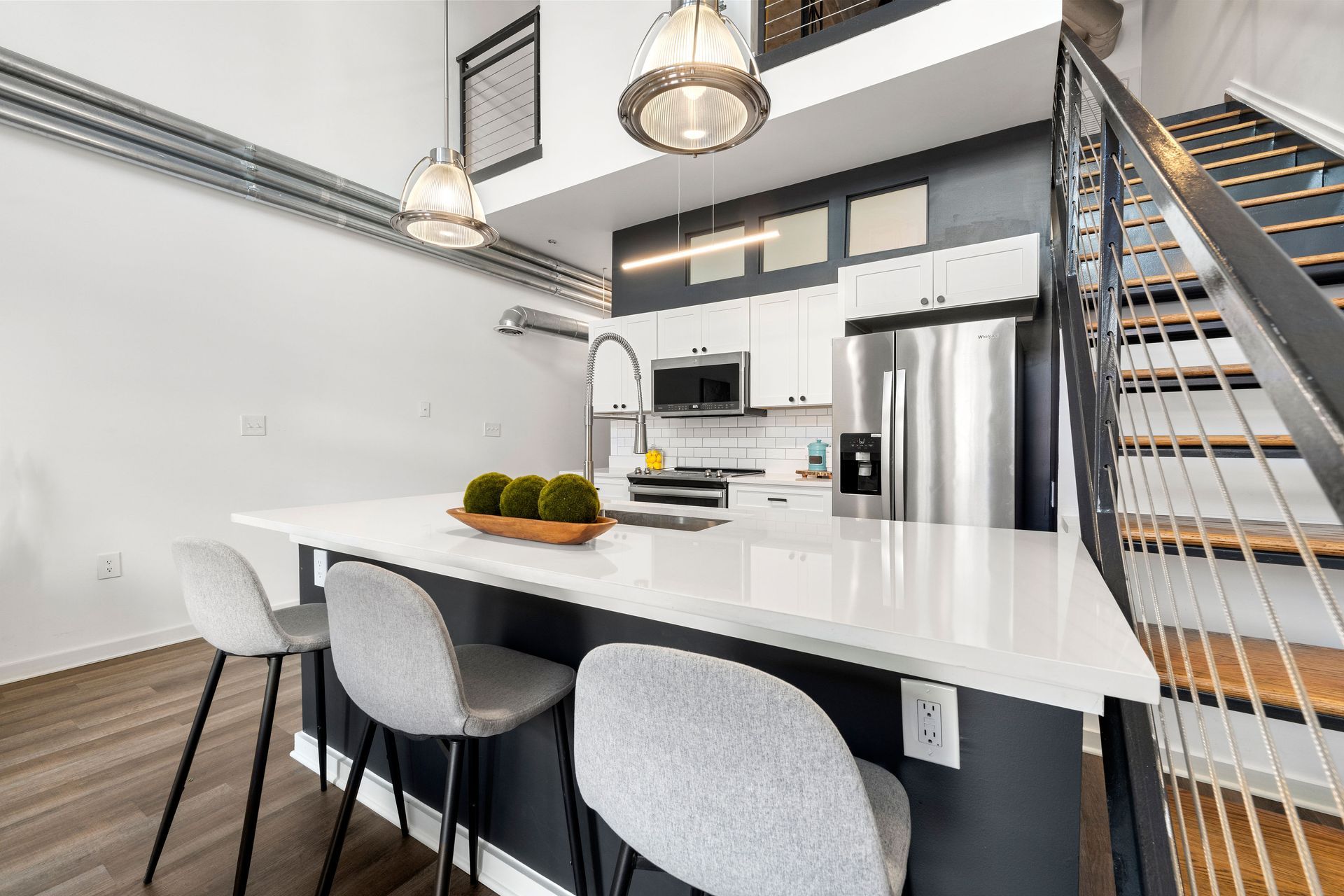 A kitchen with a large island and stairs leading up to the second floor.