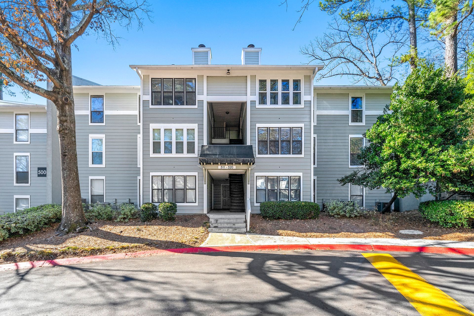 A large apartment building with a lot of windows and trees in front of it.