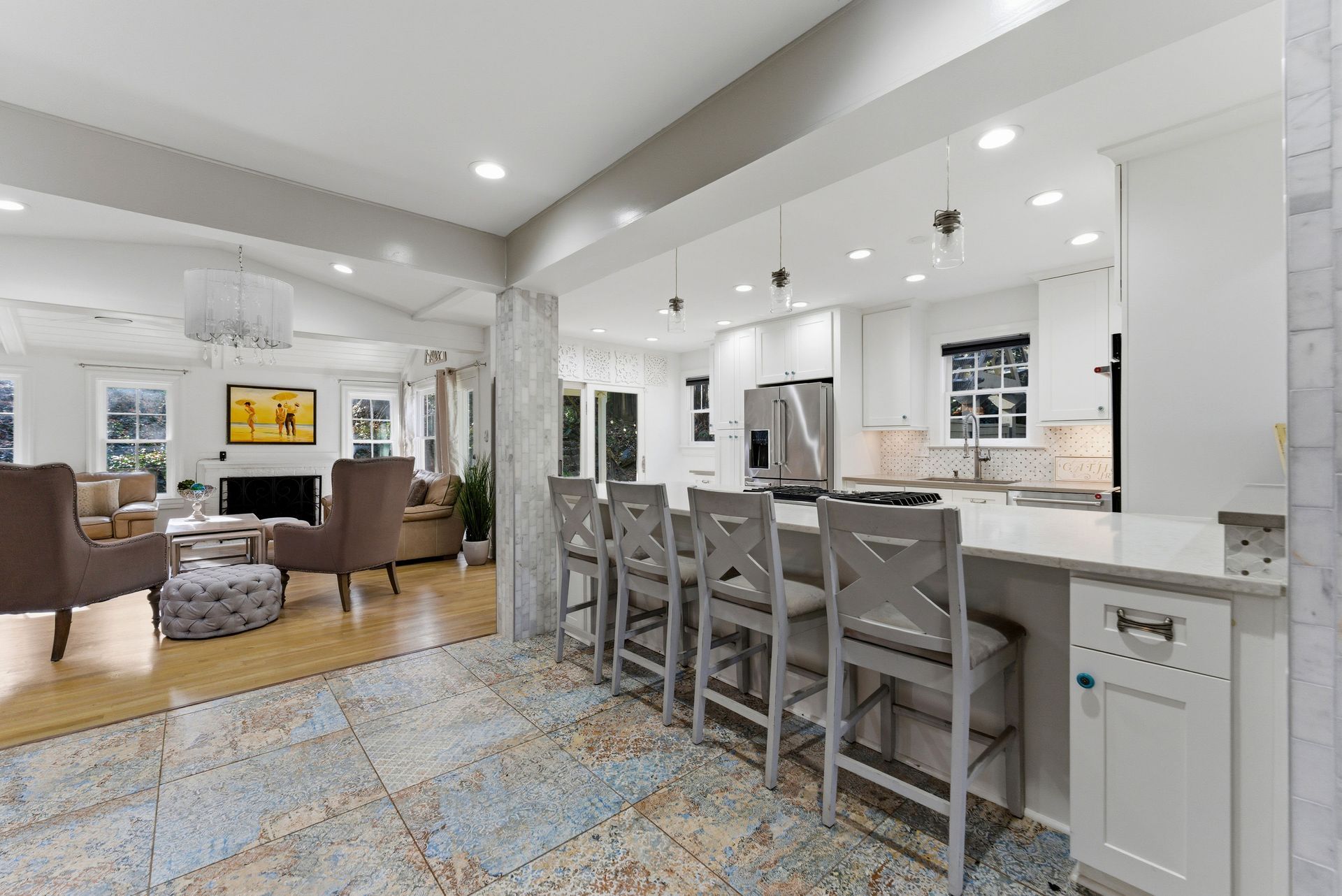 A bright, open-plan home featuring a kitchen with light grey barstools and a living room with comfortable armchairs.