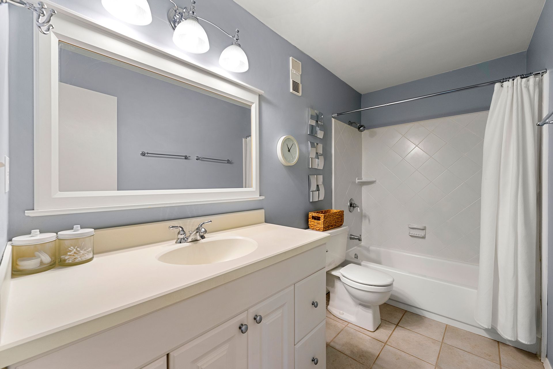 A bathroom with a sink , toilet , tub and mirror.