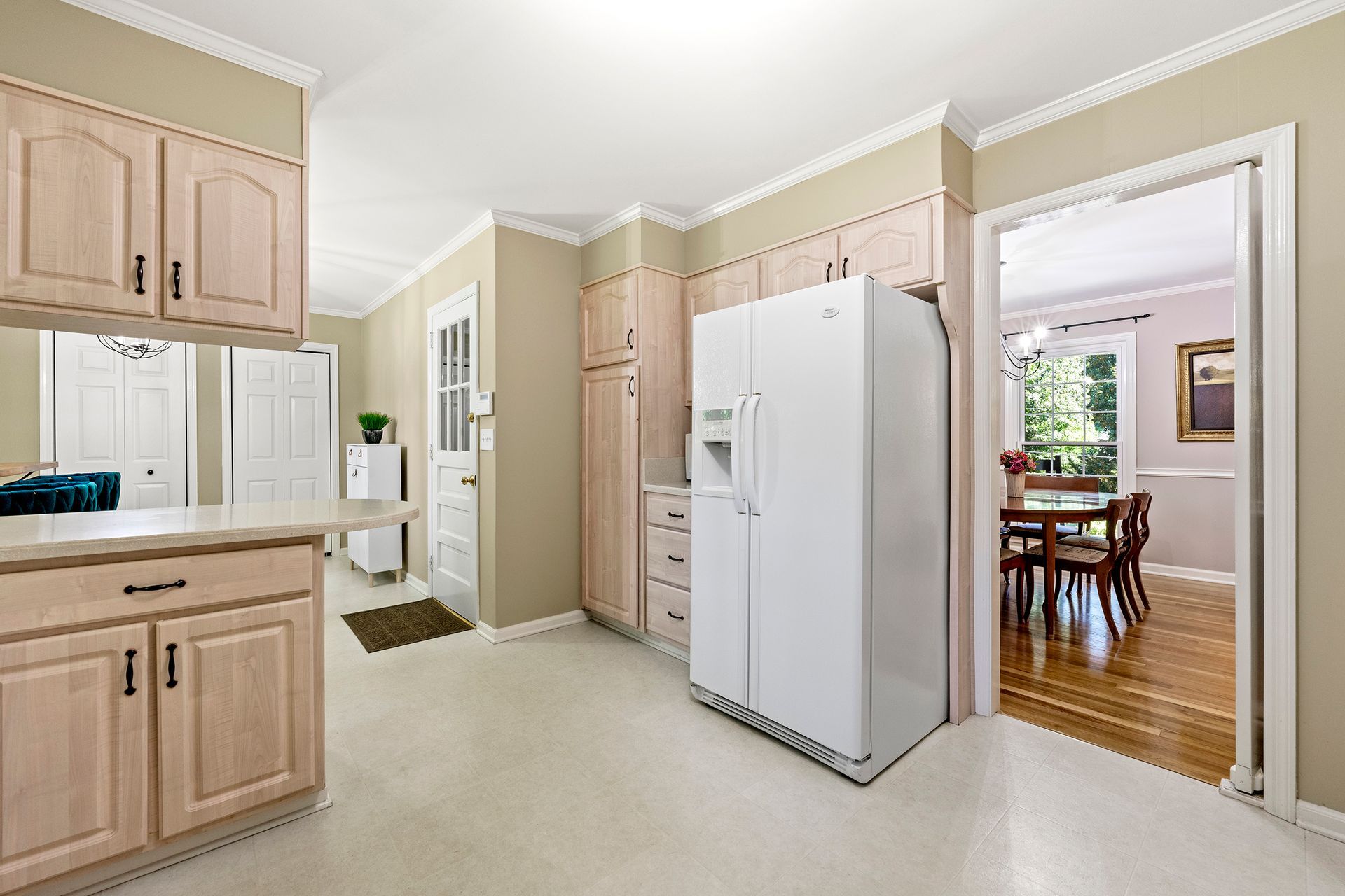 A kitchen with a white refrigerator and wooden cabinets.