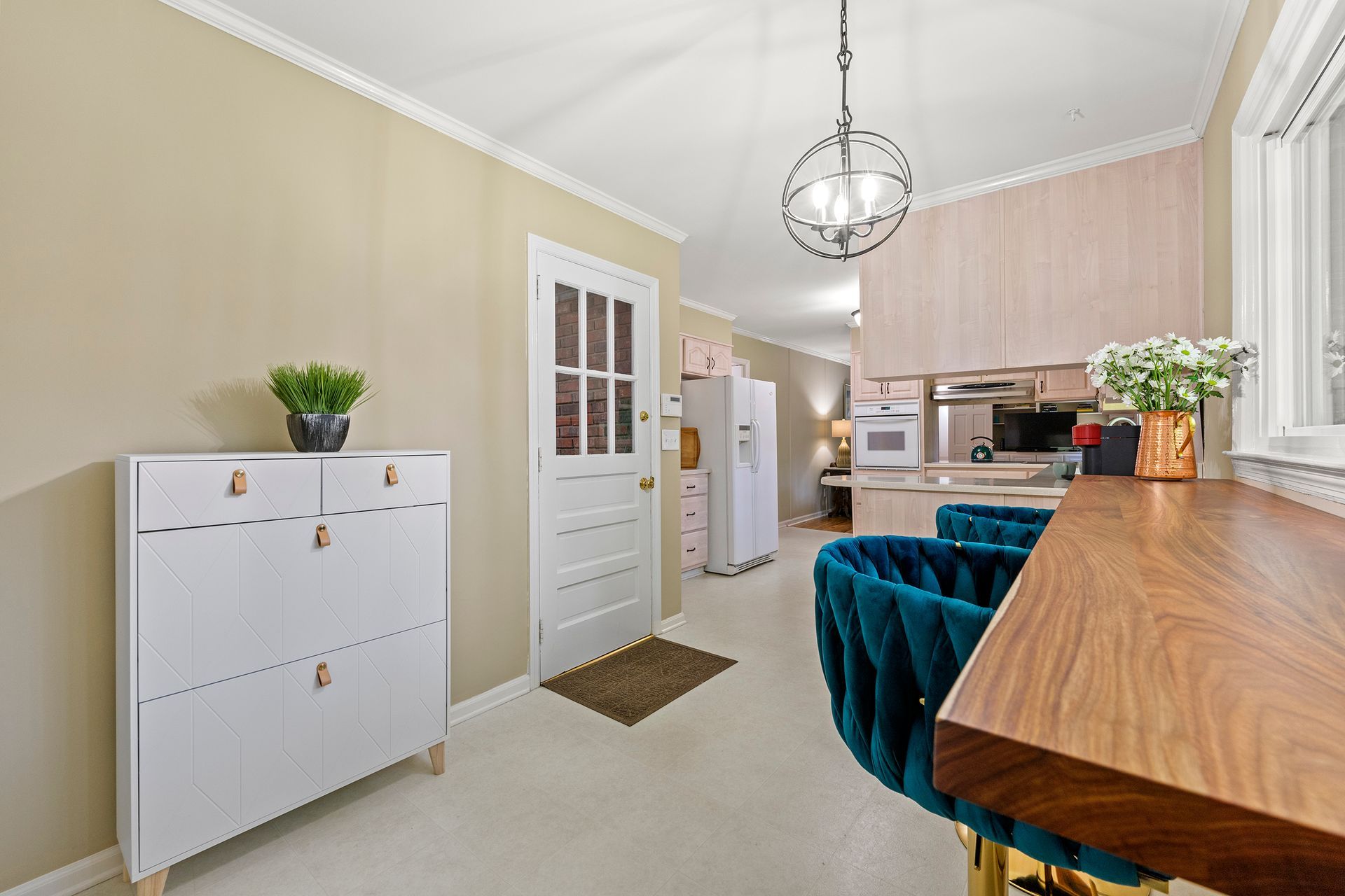 A kitchen with a wooden table and chairs and a white cabinet.
