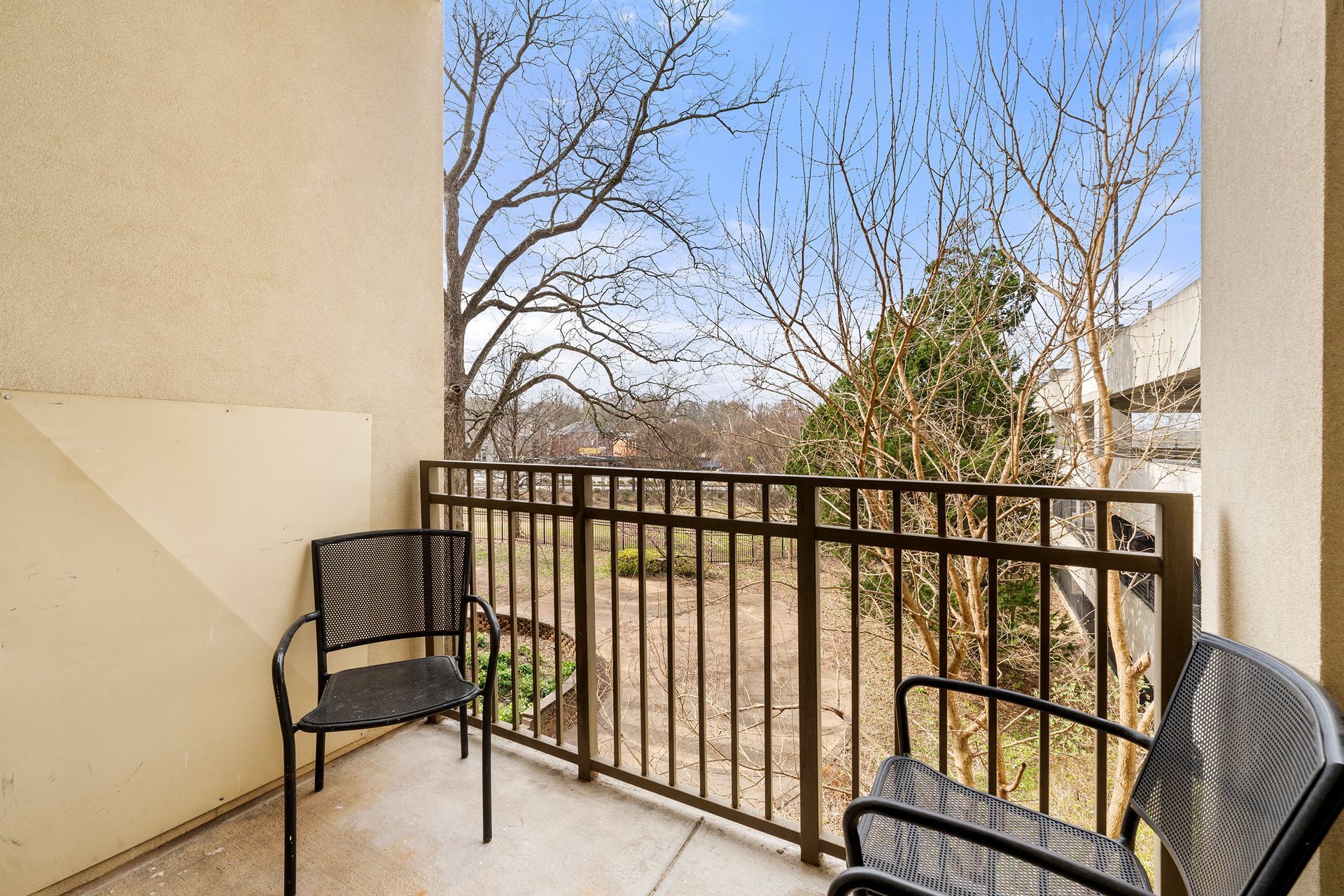 A balcony with two chairs and a table with a view of trees.