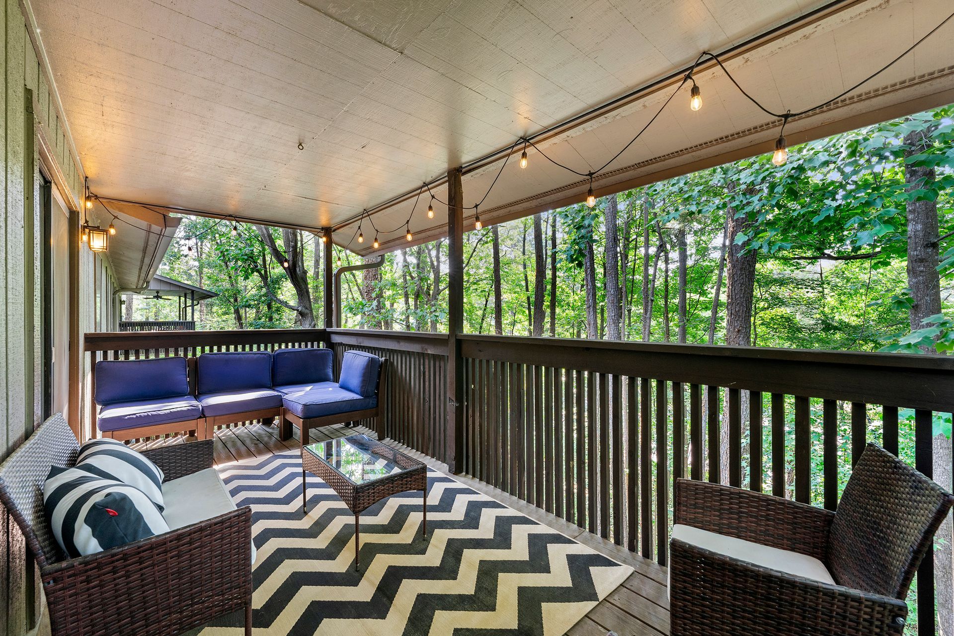 A porch with a couch , chairs , and a rug.