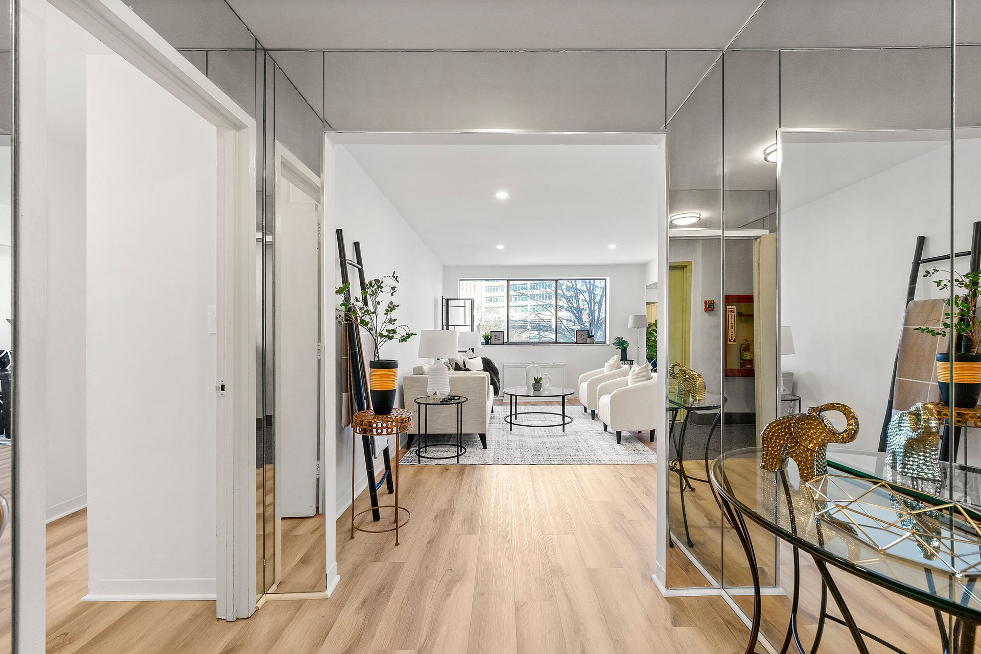A hallway with a table and mirrors leading to a living room.