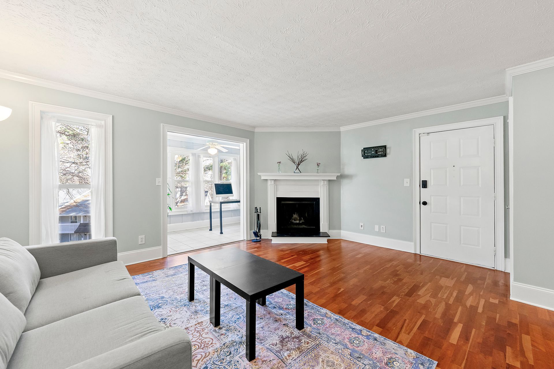A living room with a fireplace , couch , coffee table and rug.