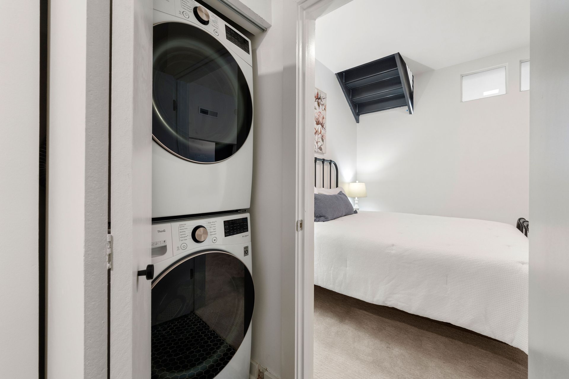 A stack of washers and dryers in a laundry room next to a bedroom.
