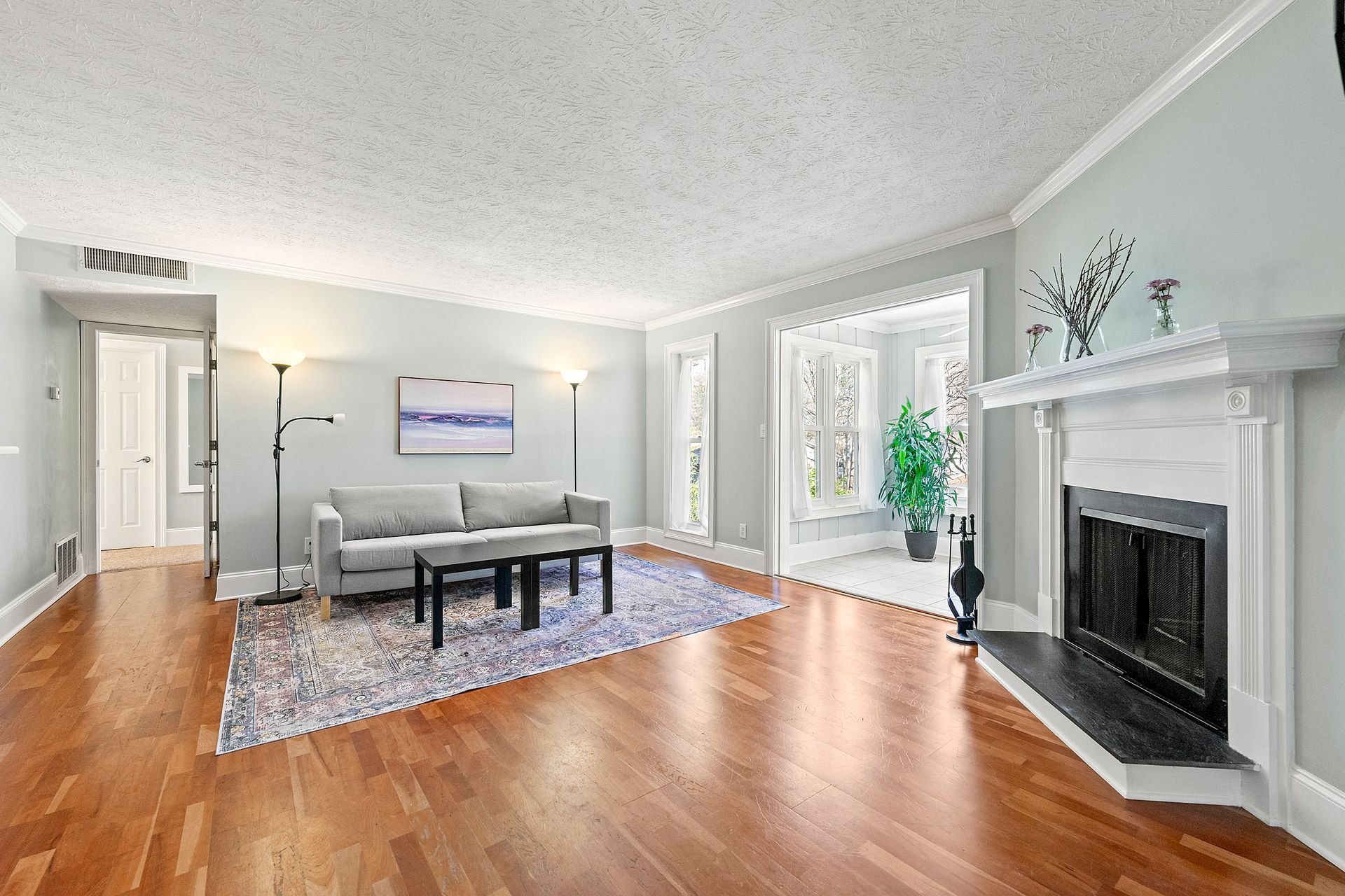 A living room with hardwood floors , a couch , and a fireplace.