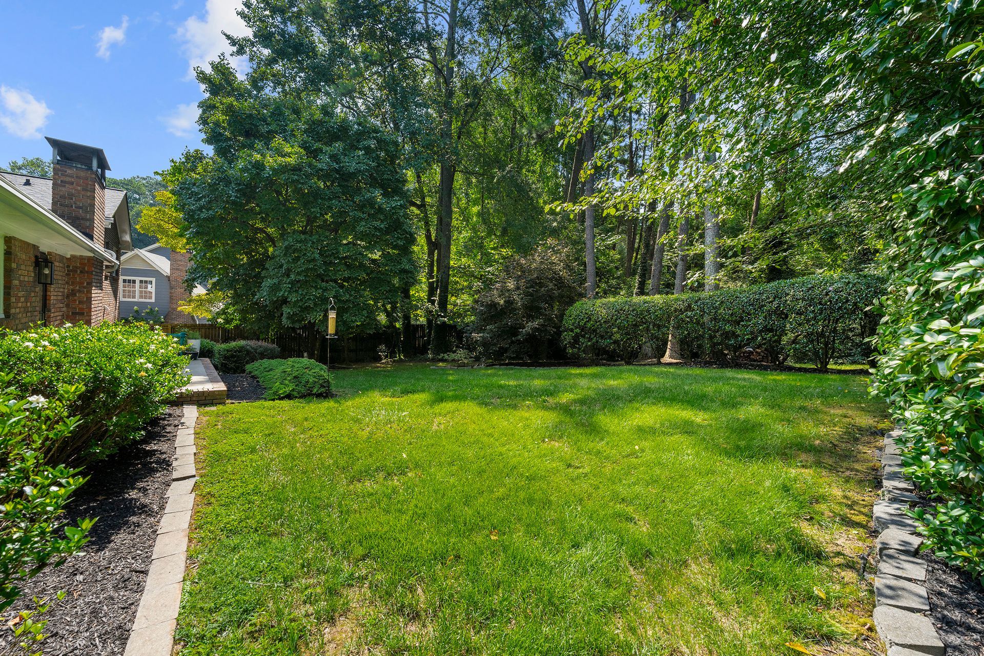 A large lush green yard with trees and bushes in front of a house.