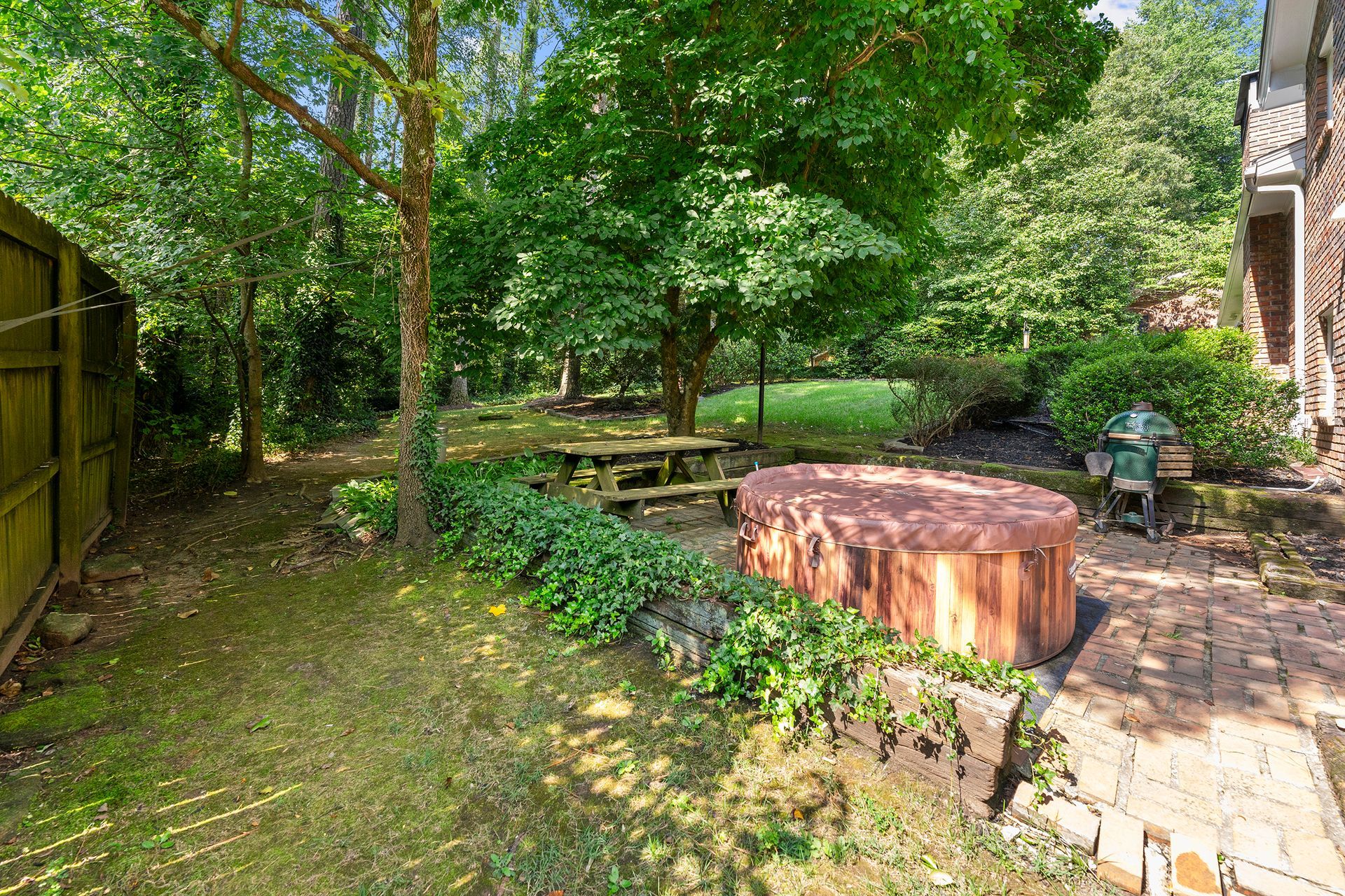 A backyard with a hot tub and a picnic table.