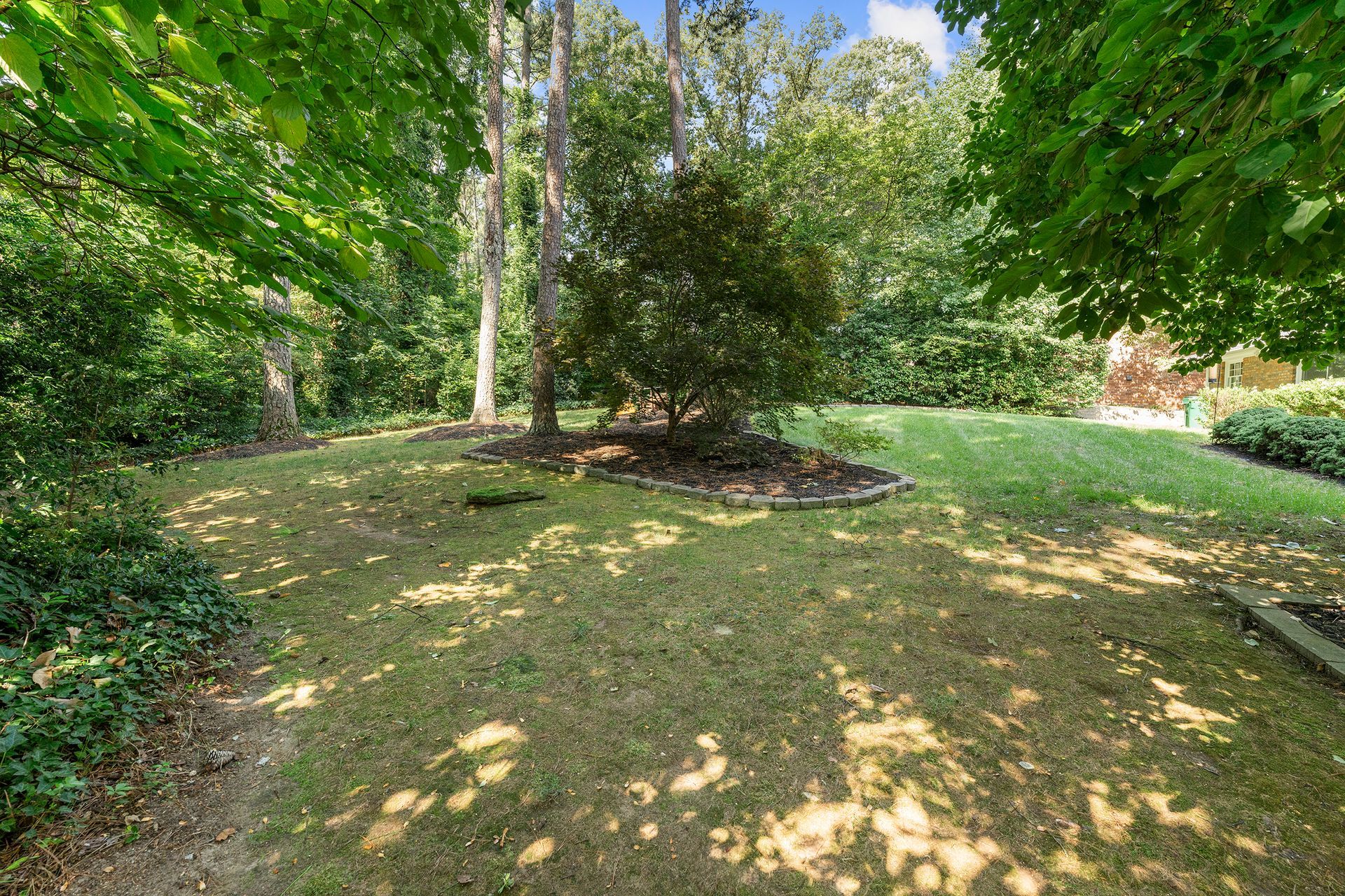 A large lush green yard surrounded by trees and bushes.