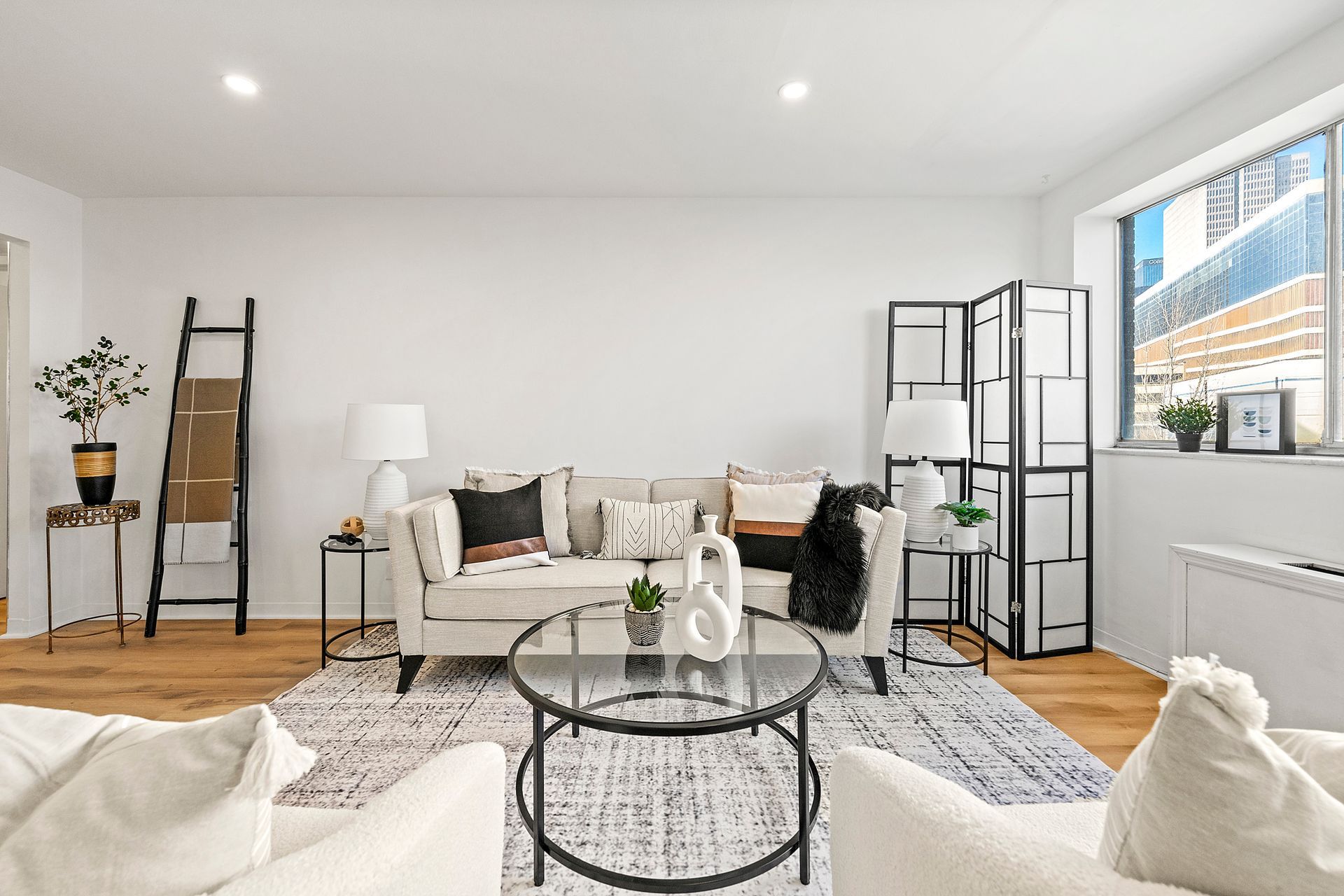 A living room with a couch , chairs , a coffee table and a window.