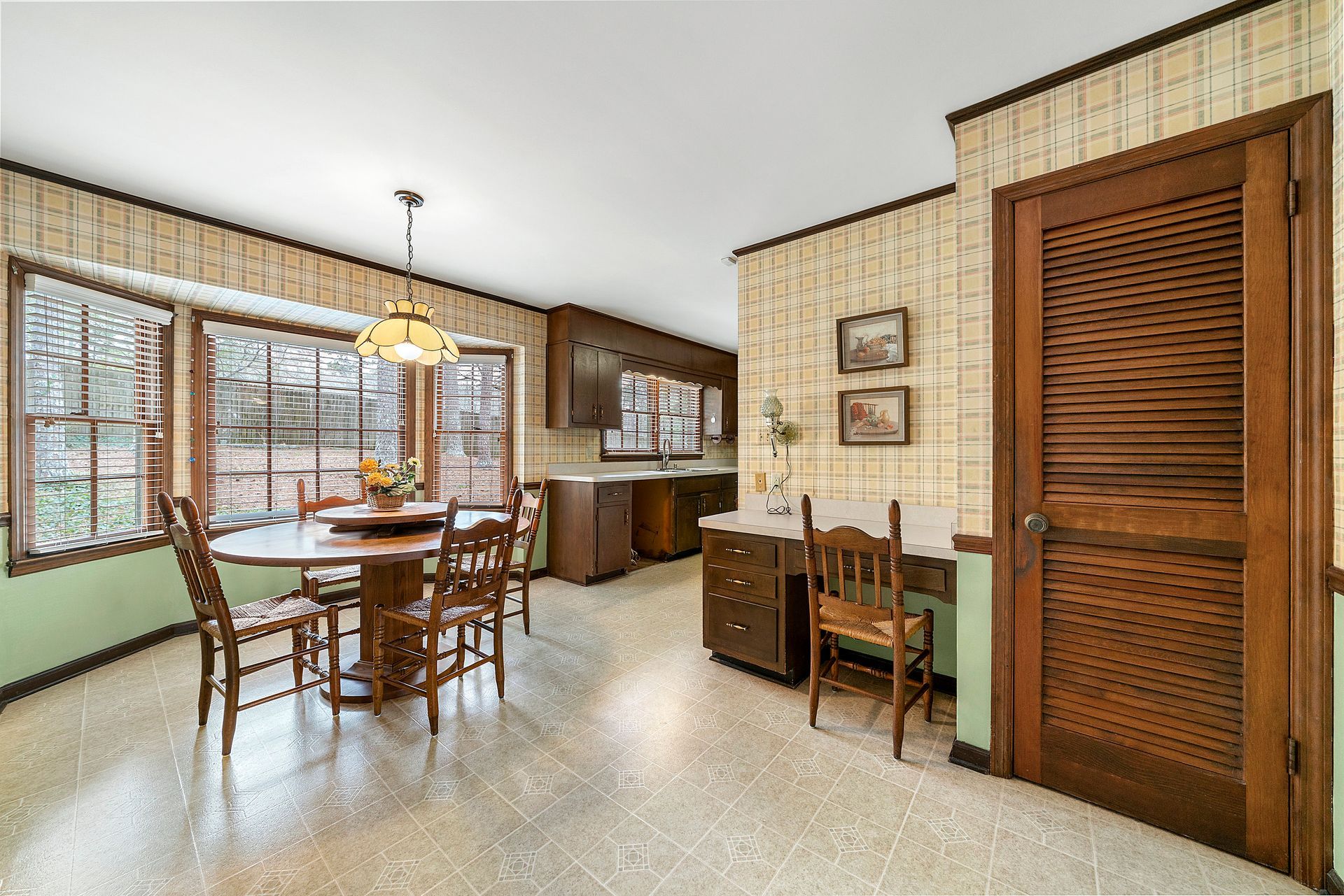 A dining room with a table and chairs and a desk.