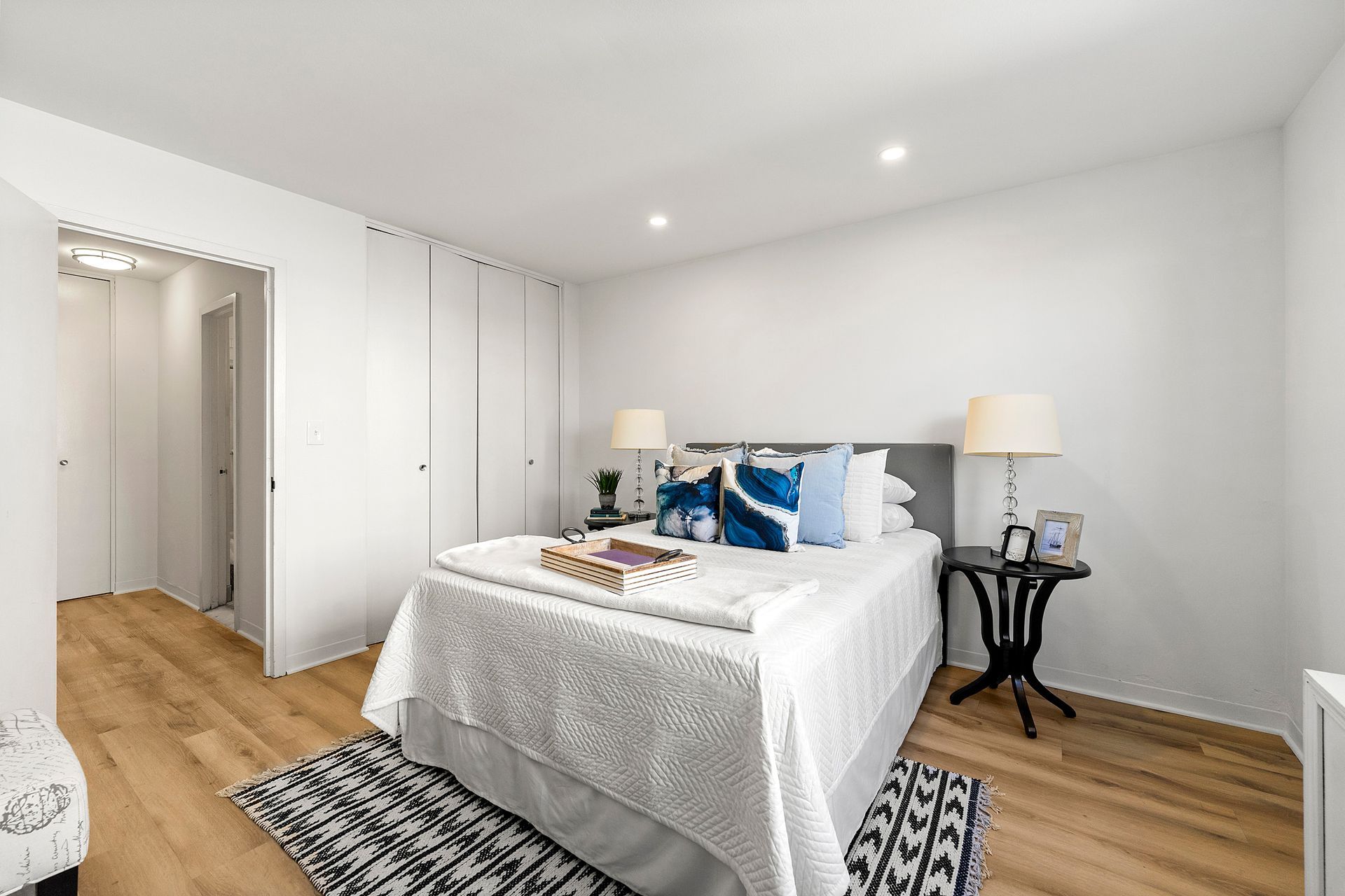 A bedroom with a large bed , two lamps , and a rug.