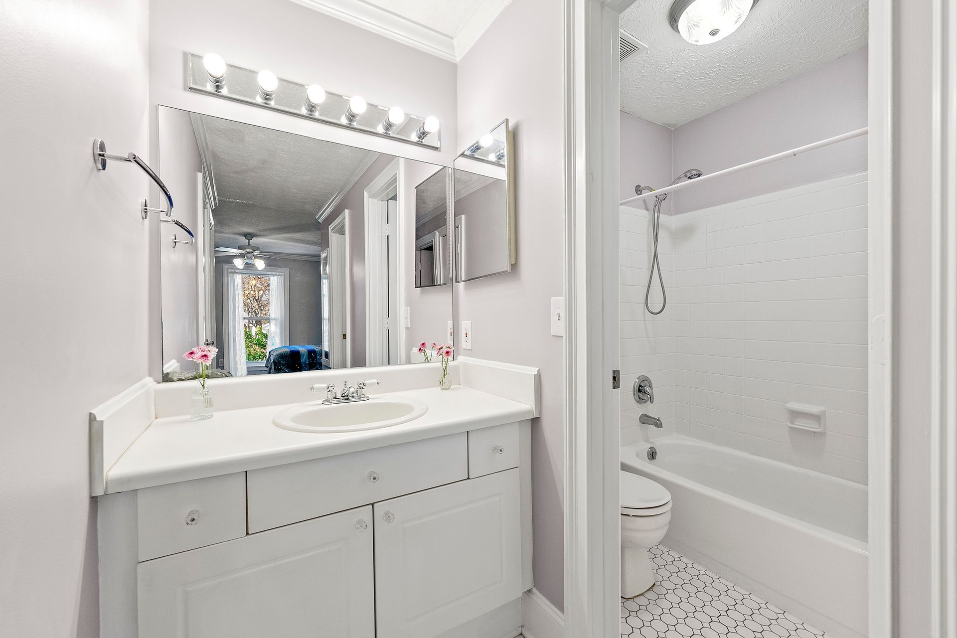 A bathroom with a sink , toilet , shower and mirror.