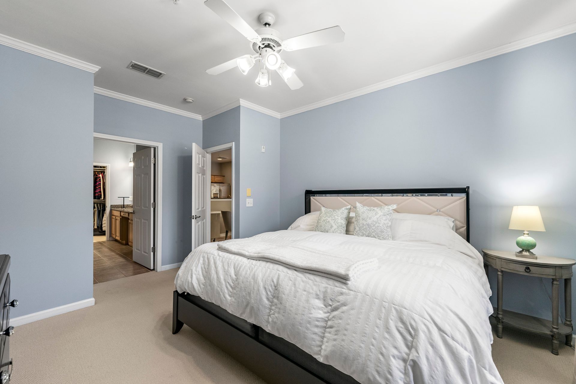 A bedroom with a large bed and a ceiling fan.