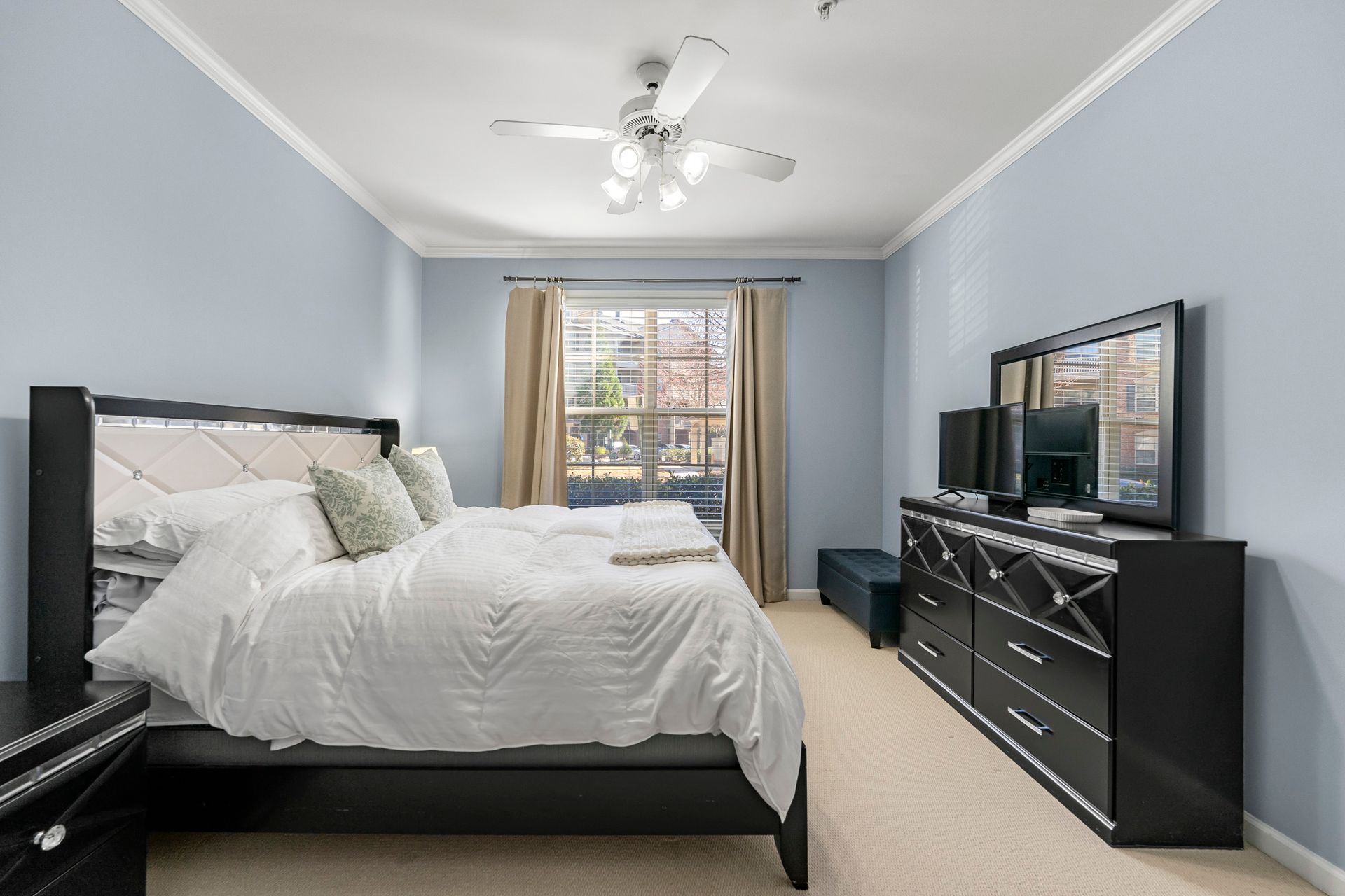 A bedroom with a bed , dresser , mirror and television.