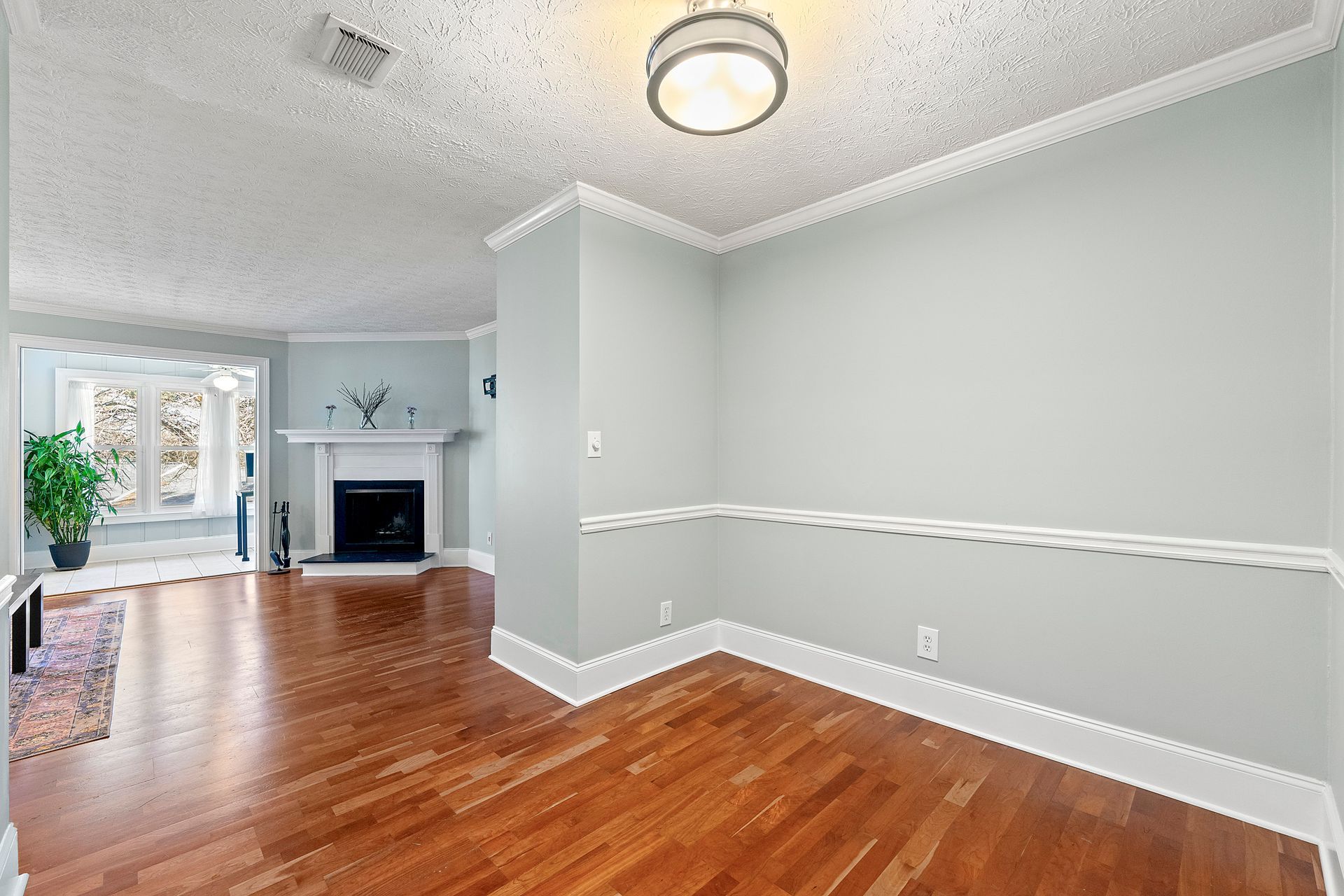 An empty living room with hardwood floors and a fireplace.