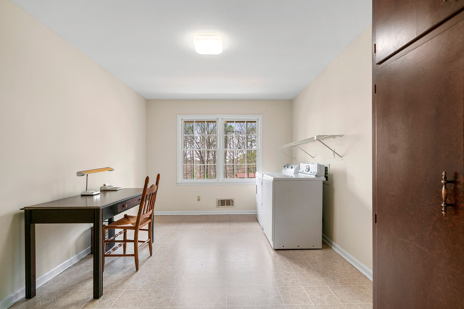 A laundry room with a desk and chairs and a washer and dryer.