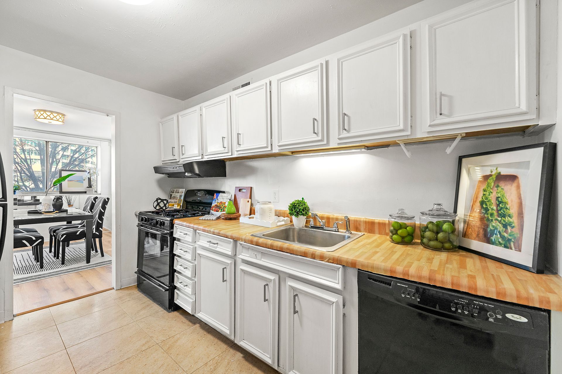 A kitchen with white cabinets , a sink , a stove and a dishwasher.