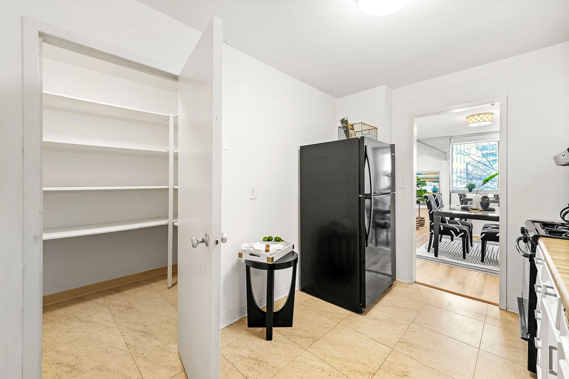 A kitchen with a black refrigerator and a pantry.