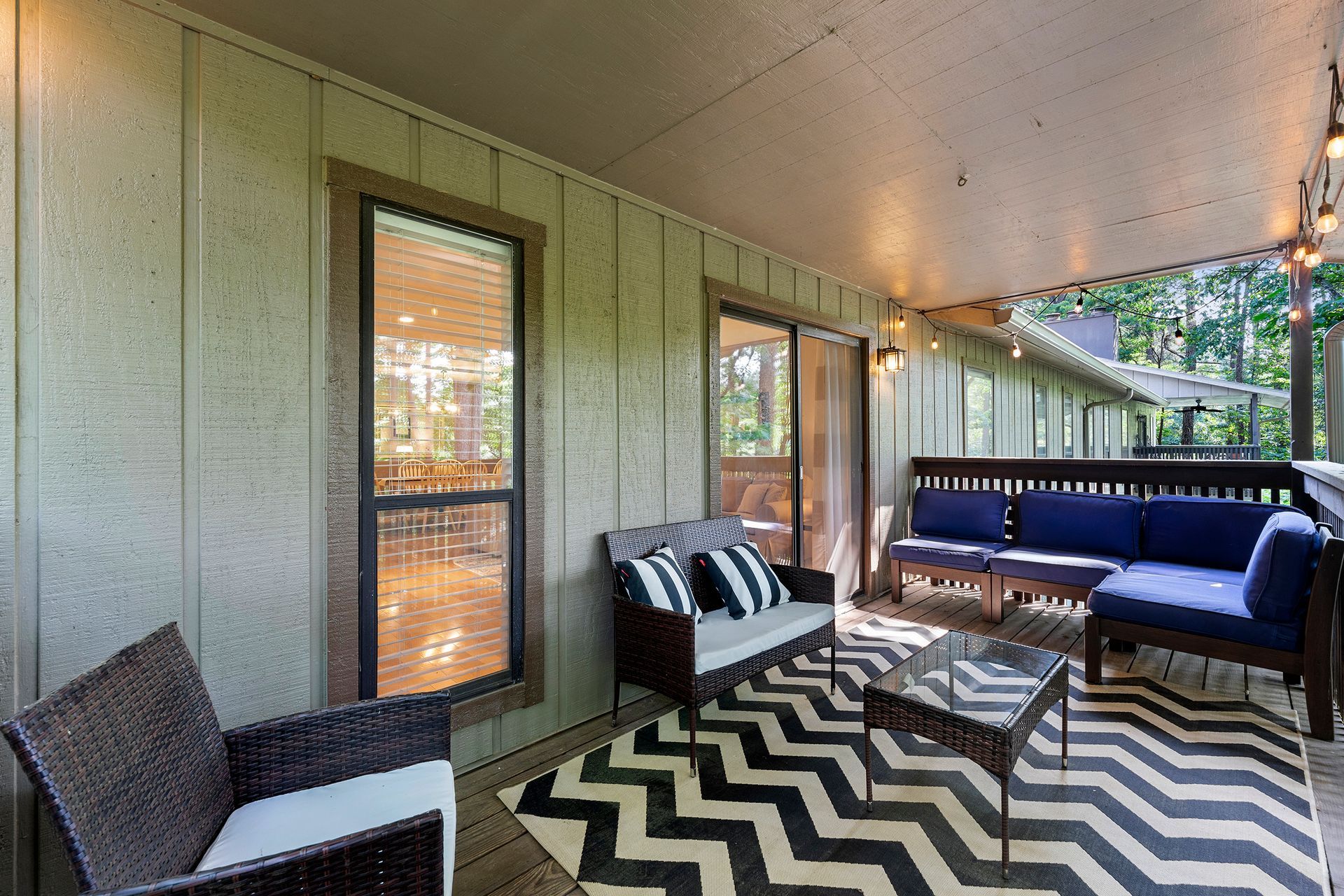 A porch with a couch , chairs , and a rug.