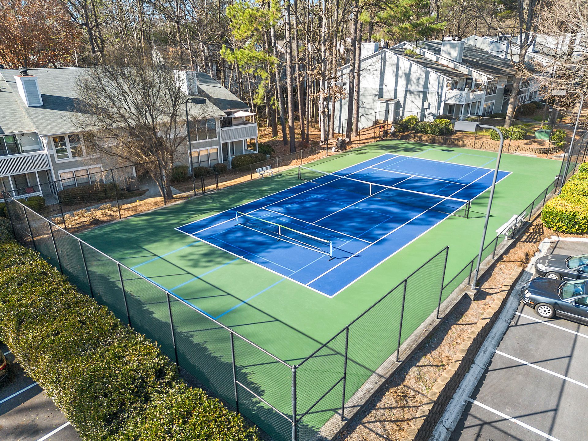 An aerial view of a tennis court with a fence around it.