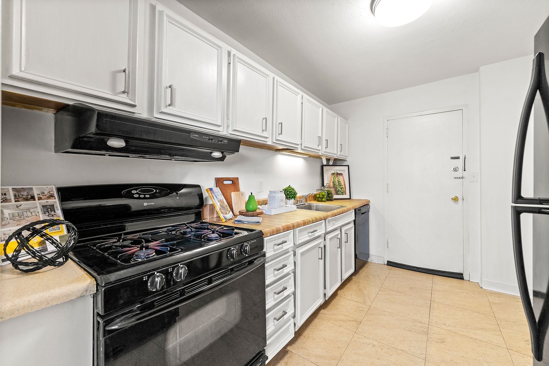 A kitchen with white cabinets , a black stove and a black refrigerator.