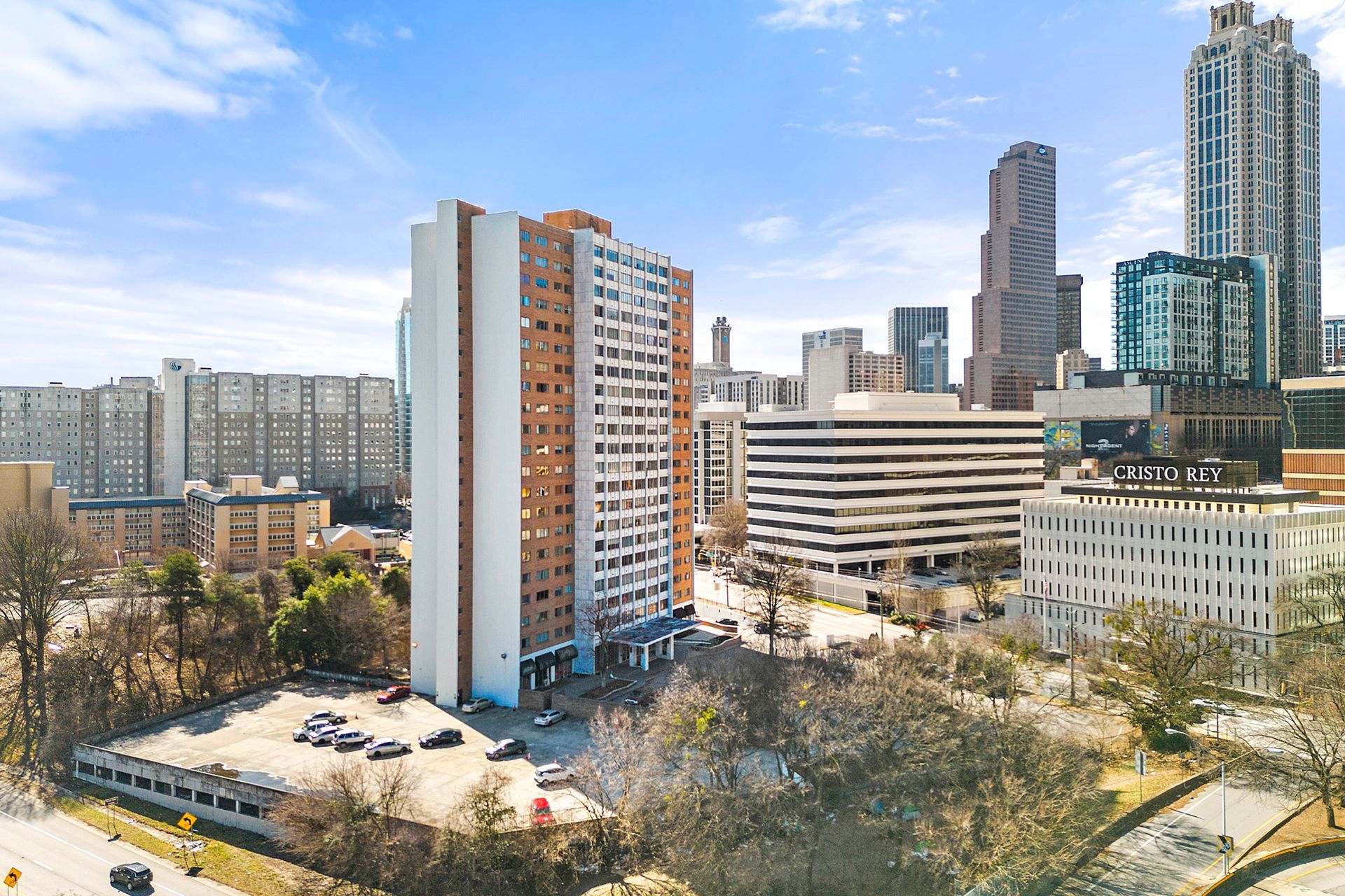 An aerial view of a city with a lot of tall buildings and a parking lot in the foreground.