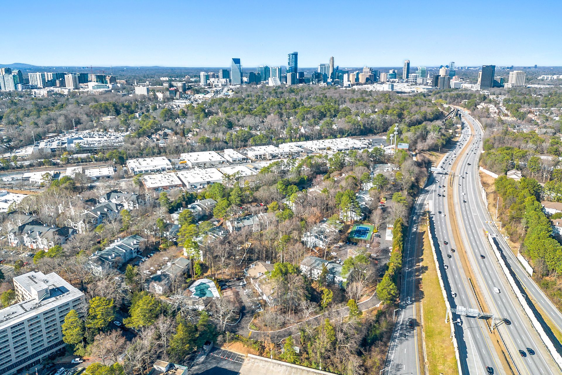 An aerial view of a highway leading to a city with a city skyline in the background.