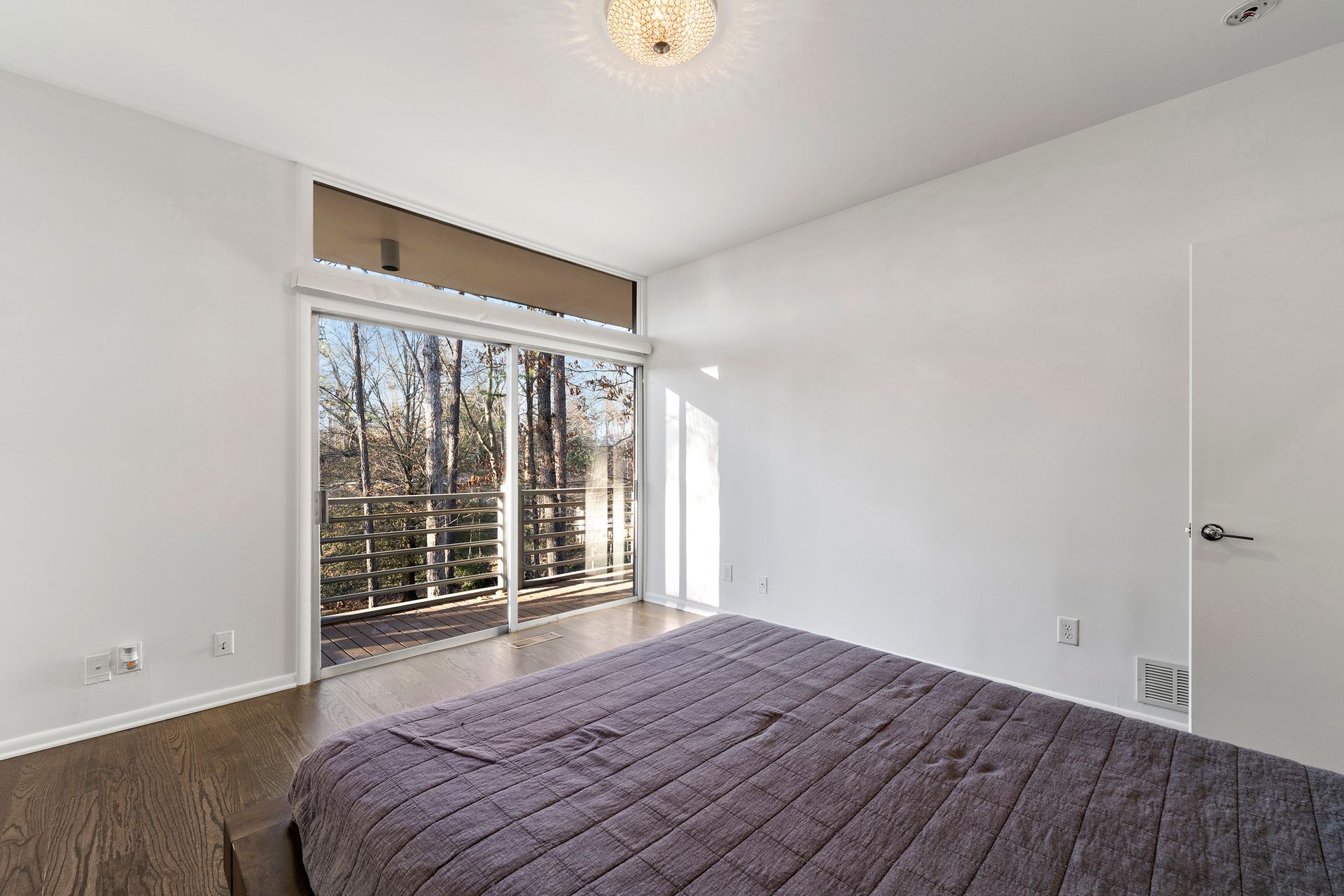 A bedroom with a large bed and sliding glass doors.