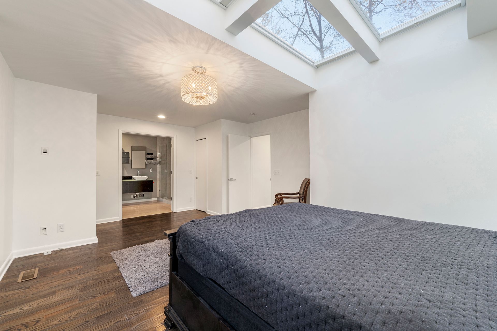 A bedroom with a large bed and a skylight in the ceiling.