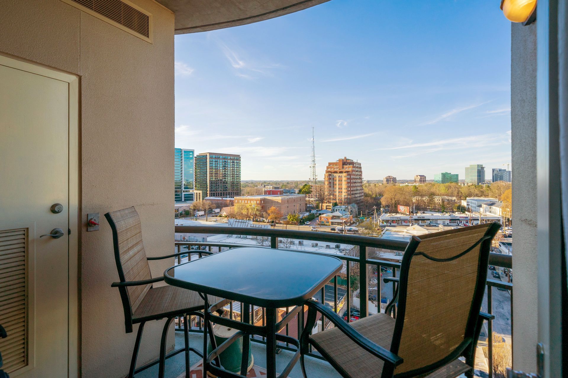 A balcony with a table and chairs overlooking a city.