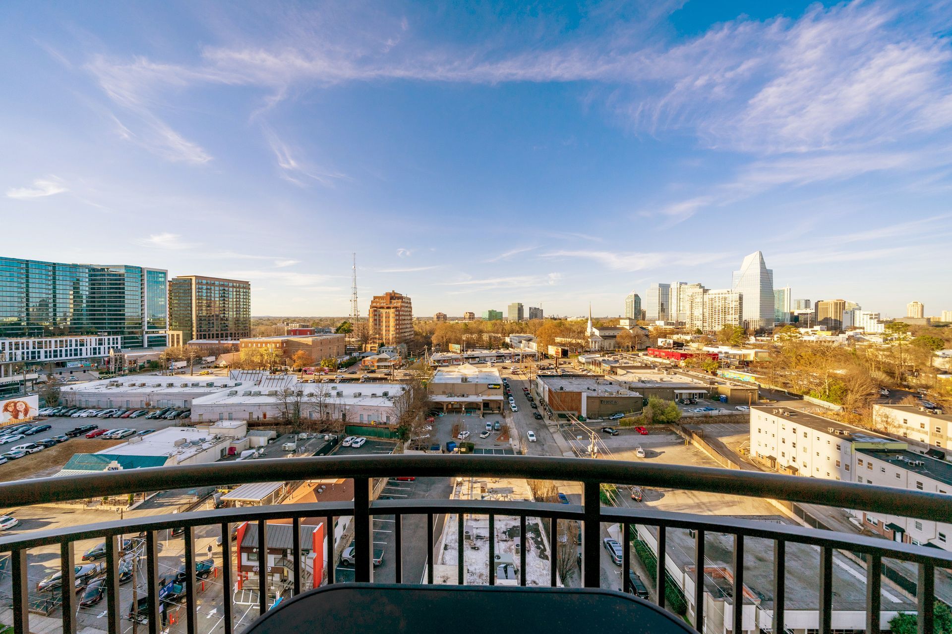 A view of a city from a balcony with a table and chairs.